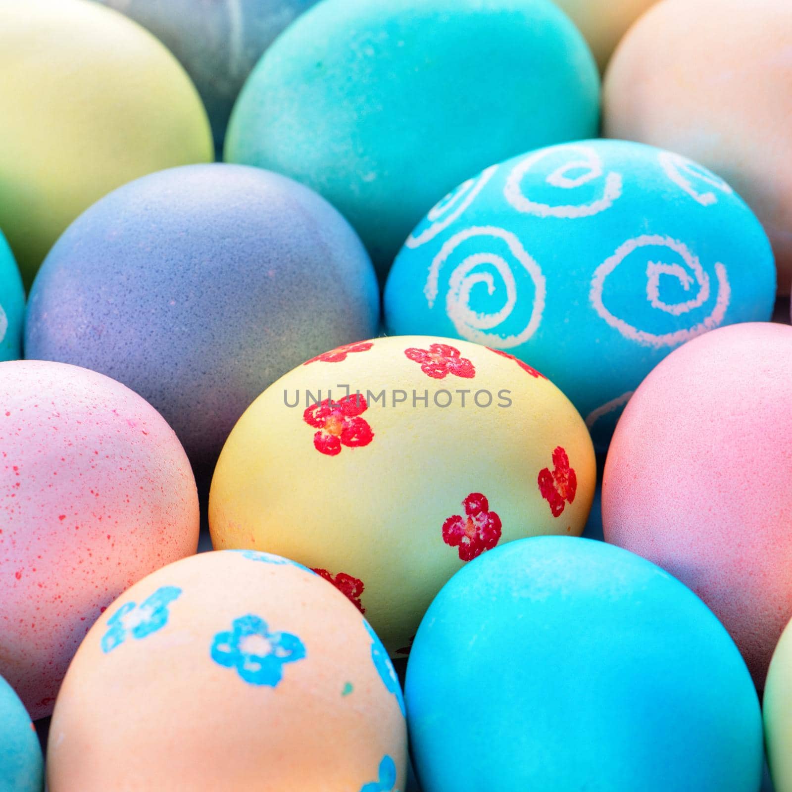 Colorful Easter eggs dyed by colored water with beautiful pattern on a pale blue background, design concept of holiday activity, top view, full frame.