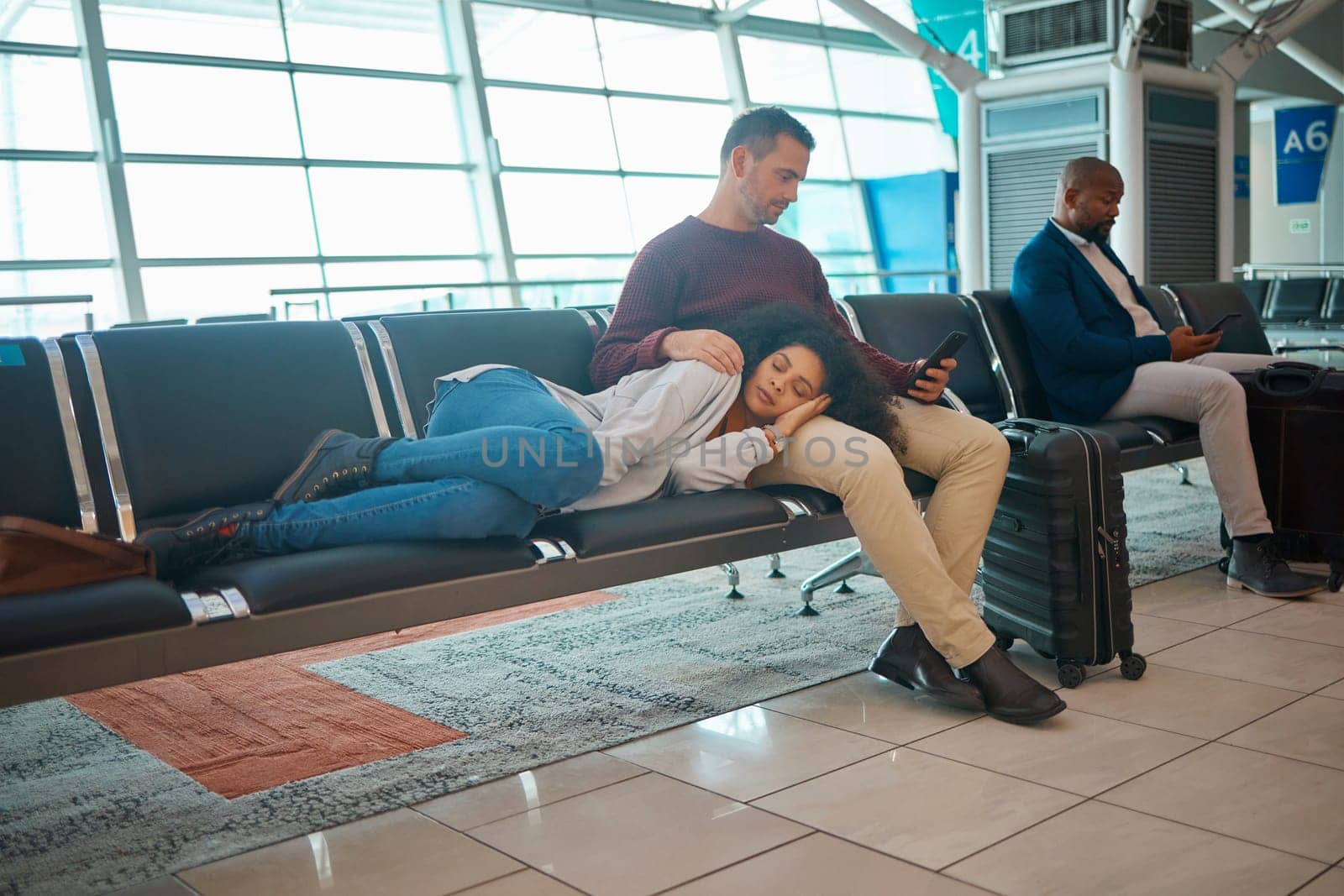 Tired, delay and couple at the airport for a flight, waiting and sitting in the lounge on a phone. Immigration, relax and woman sleeping with a man reading on a mobile while traveling for holiday by YuriArcurs