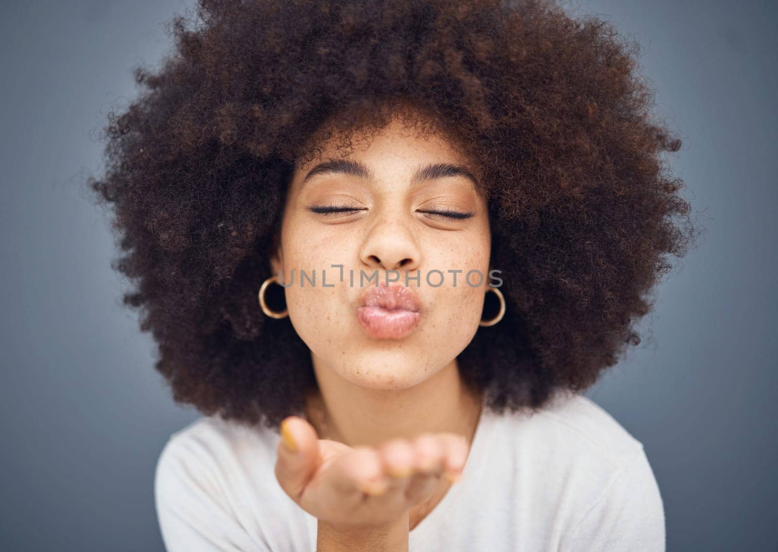 Kissing, love and romance with a black woman blowing a kiss in studio on a gray background for romantic affection. Beauty, lips and flirt with an attractive young female making a mouth gesture by YuriArcurs