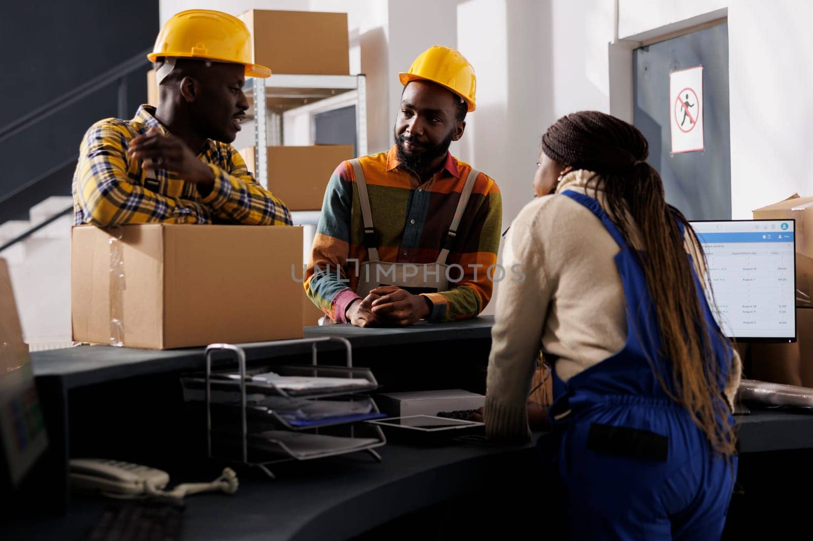 Warehouse workers holding parcel at reception, discussing package transportation. Freight distribution manager receiving cardboard box ready for shipment at checkout desk