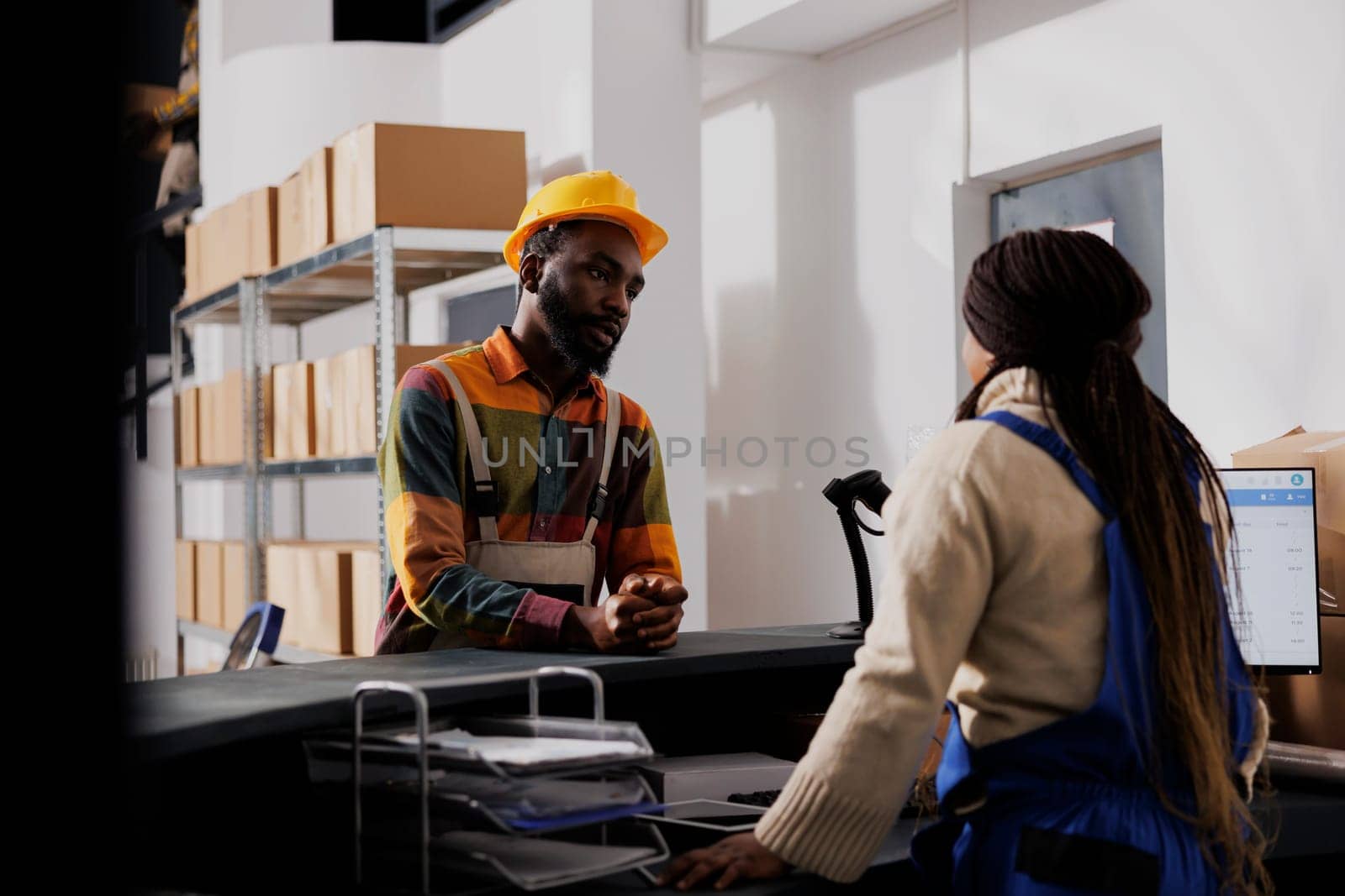 Warehouse workers standing at counter desk discussing shipment management by DCStudio