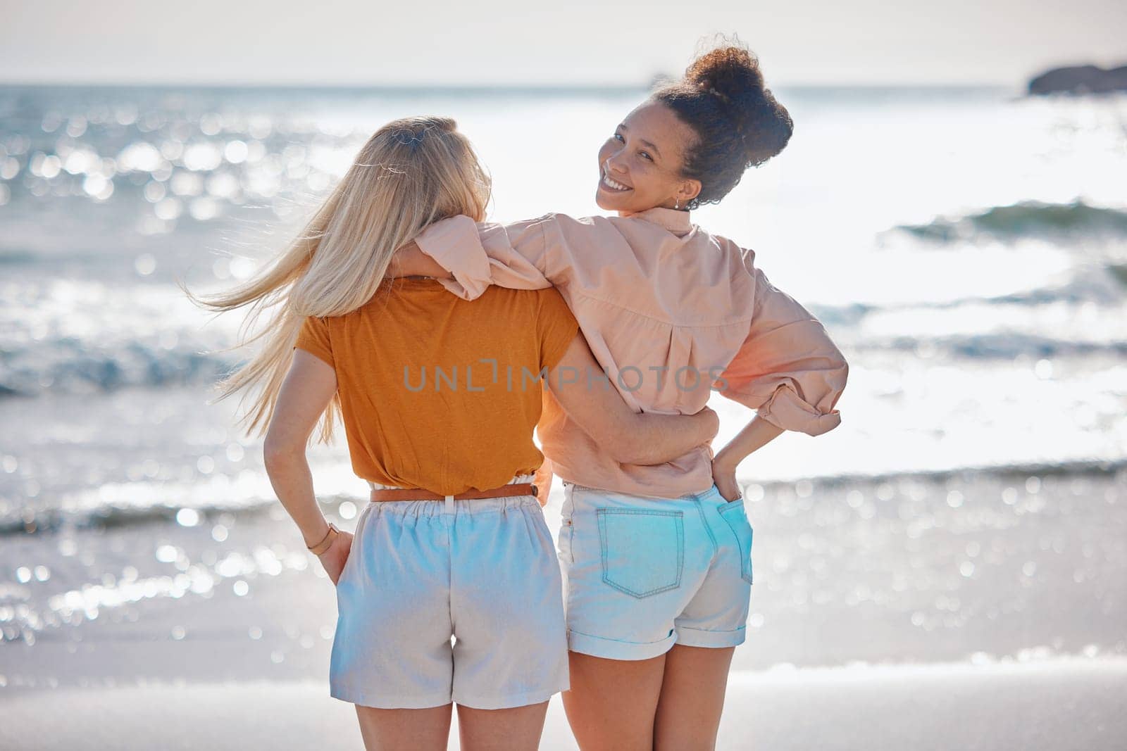 Back view, hug or friends at a beach to relax talking or laughing on summer holiday vacation in Florida, USA. Bonding, happy or young women enjoy traveling to sea or ocean on girls trips with freedom by YuriArcurs