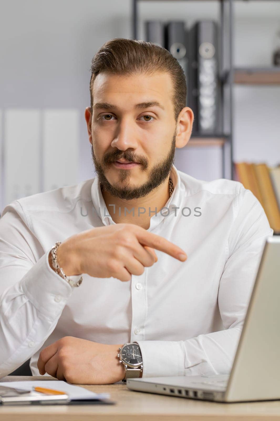 Business man working online on laptop, finishing work, positive feedback, like, approving application, good offer sale advertisement. Freelancer guy at office looking at camera, talking. Vertical