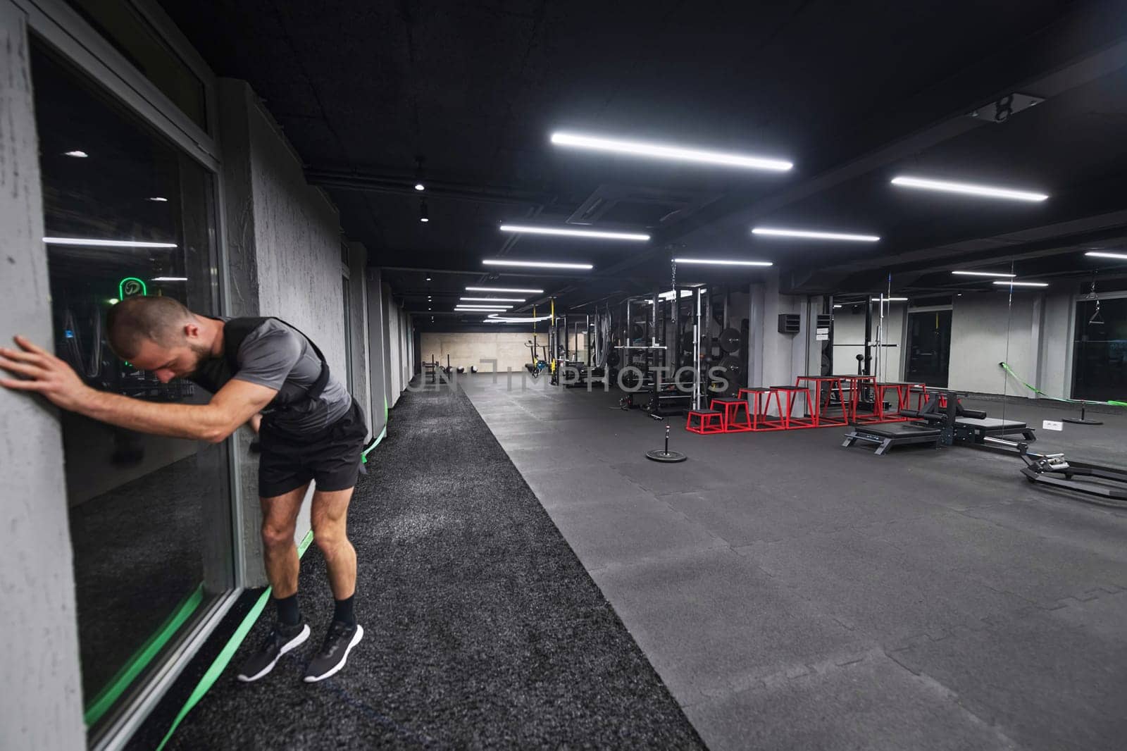 A muscular man is focused on working out with dumbbells in a modern gym, showing his determination and commitment to his fitness regimen