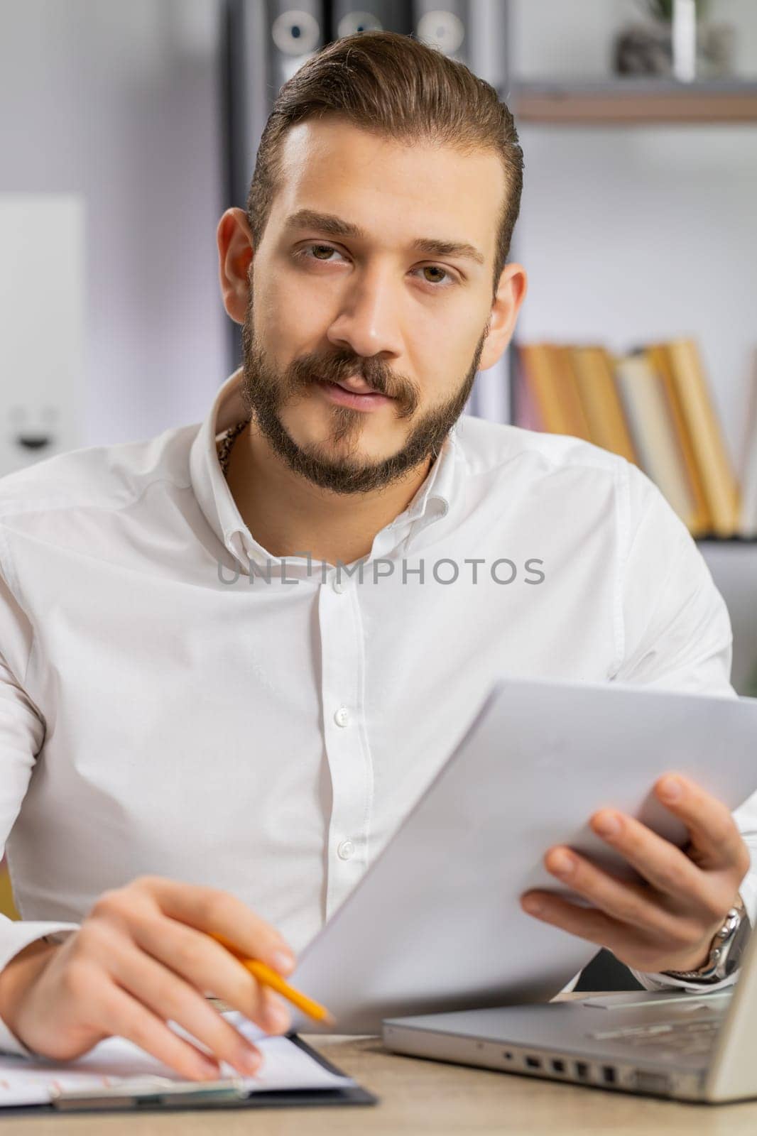 Businessman ceo reading business contract, planning project, analyzing resume, satisfied with good paperwork results. Man at office looking at camera talking, online conversation interview. Vertical