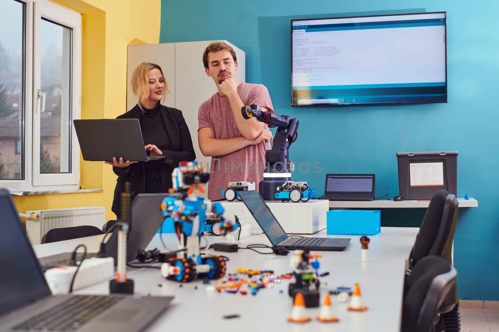 A group of colleagues working together in a robotics laboratory, focusing on the intricate fields of robotics and 3D printing. Showcase their dedication to innovation, as they engage in research, development, engineering, and precision work.