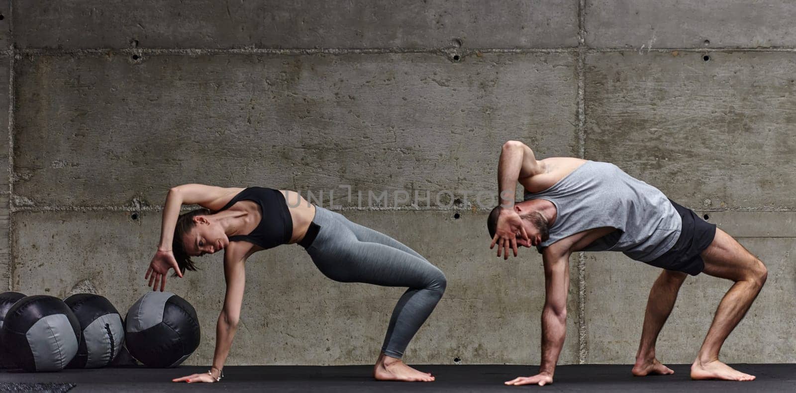 An attractive couple in the gym engaging in various stretching exercises together, showcasing their dedication to fitness, flexibility, and overall well-being. With synchronized movements, they demonstrate coordination, balance, and endurance while supporting and motivating each other on their fitness journey by dotshock