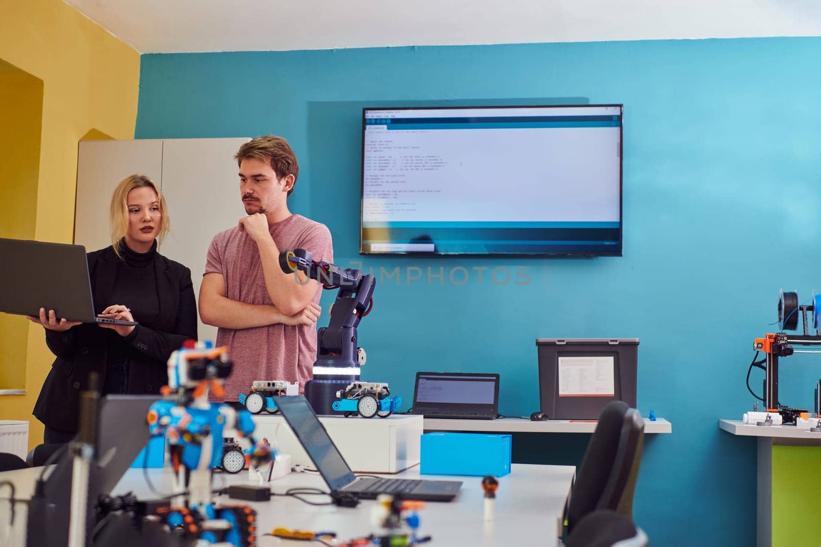 A group of colleagues working together in a robotics laboratory, focusing on the intricate fields of robotics and 3D printing. Showcase their dedication to innovation, as they engage in research, development, engineering, and precision work by dotshock