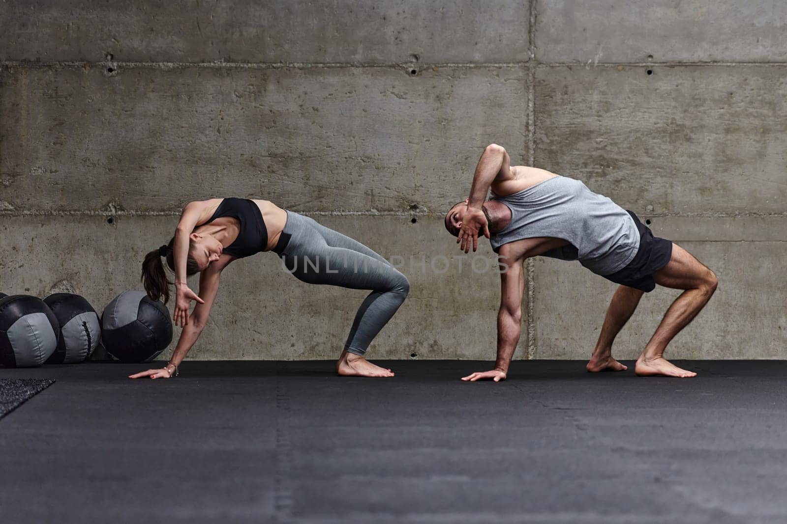 An attractive couple in the gym engaging in various stretching exercises together, showcasing their dedication to fitness, flexibility, and overall well-being. With synchronized movements, they demonstrate coordination, balance, and endurance while supporting and motivating each other on their fitness journey by dotshock