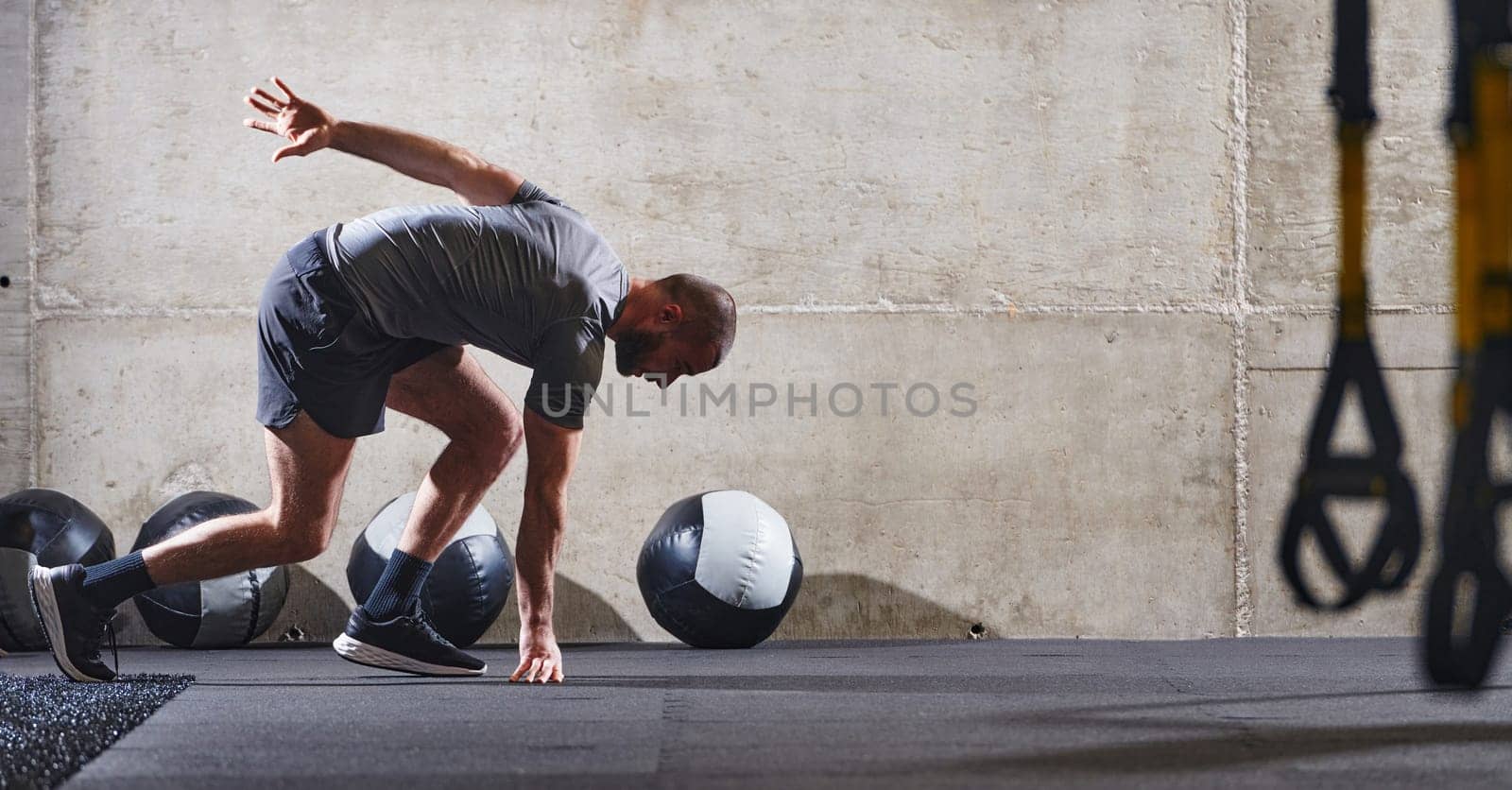 A muscular man captured in air as he jumps in a modern gym, showcasing his athleticism, power, and determination through a highintensity fitness routine.