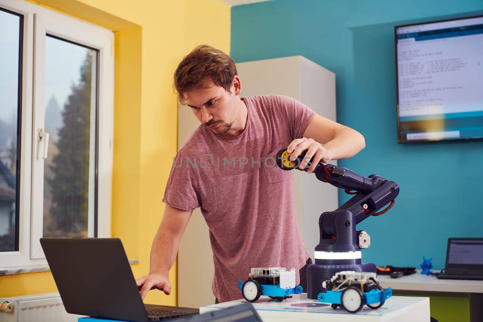 A student testing his new invention of a robotic arm in the laboratory, showcasing the culmination of his research and technological prowess