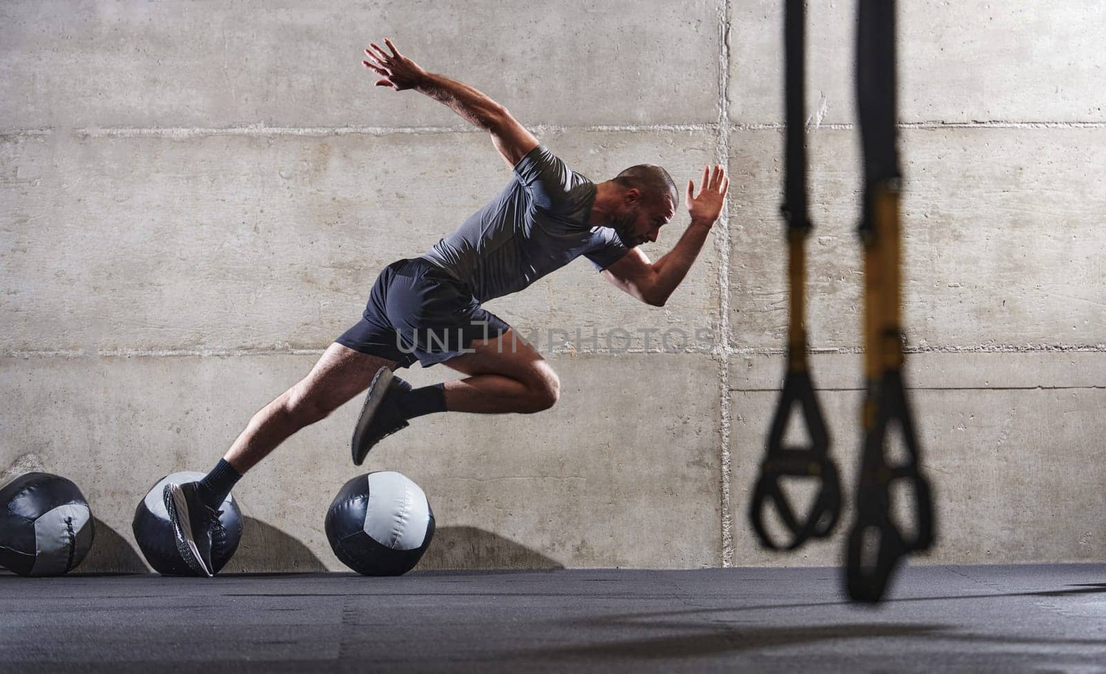 A muscular man captured in air as he jumps in a modern gym, showcasing his athleticism, power, and determination through a highintensity fitness routine.