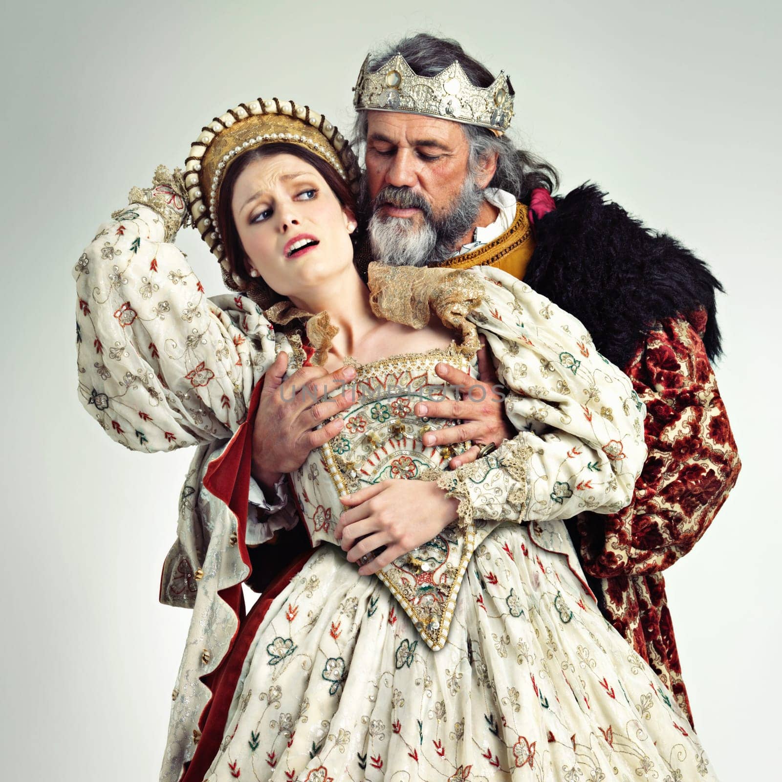 Theater, king and queen in costume with violence in in crown and renaissance clothes in studio. Art, cosplay and larp, couple in medieval play, royal history character and woman in distress with man