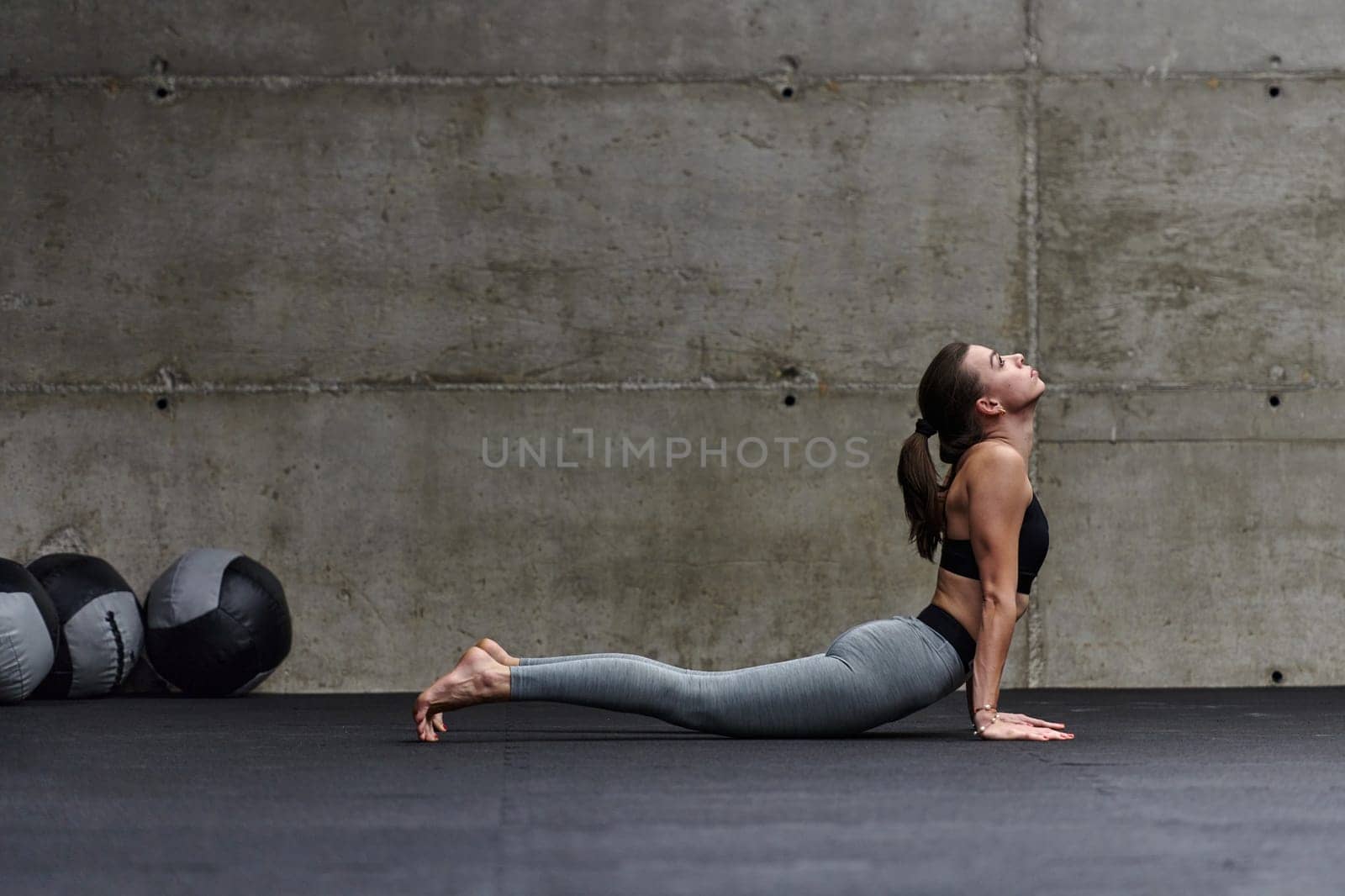 Fit woman in a modern gym working flexibility and strength through various exercises, demonstrating her commitment to fitness.