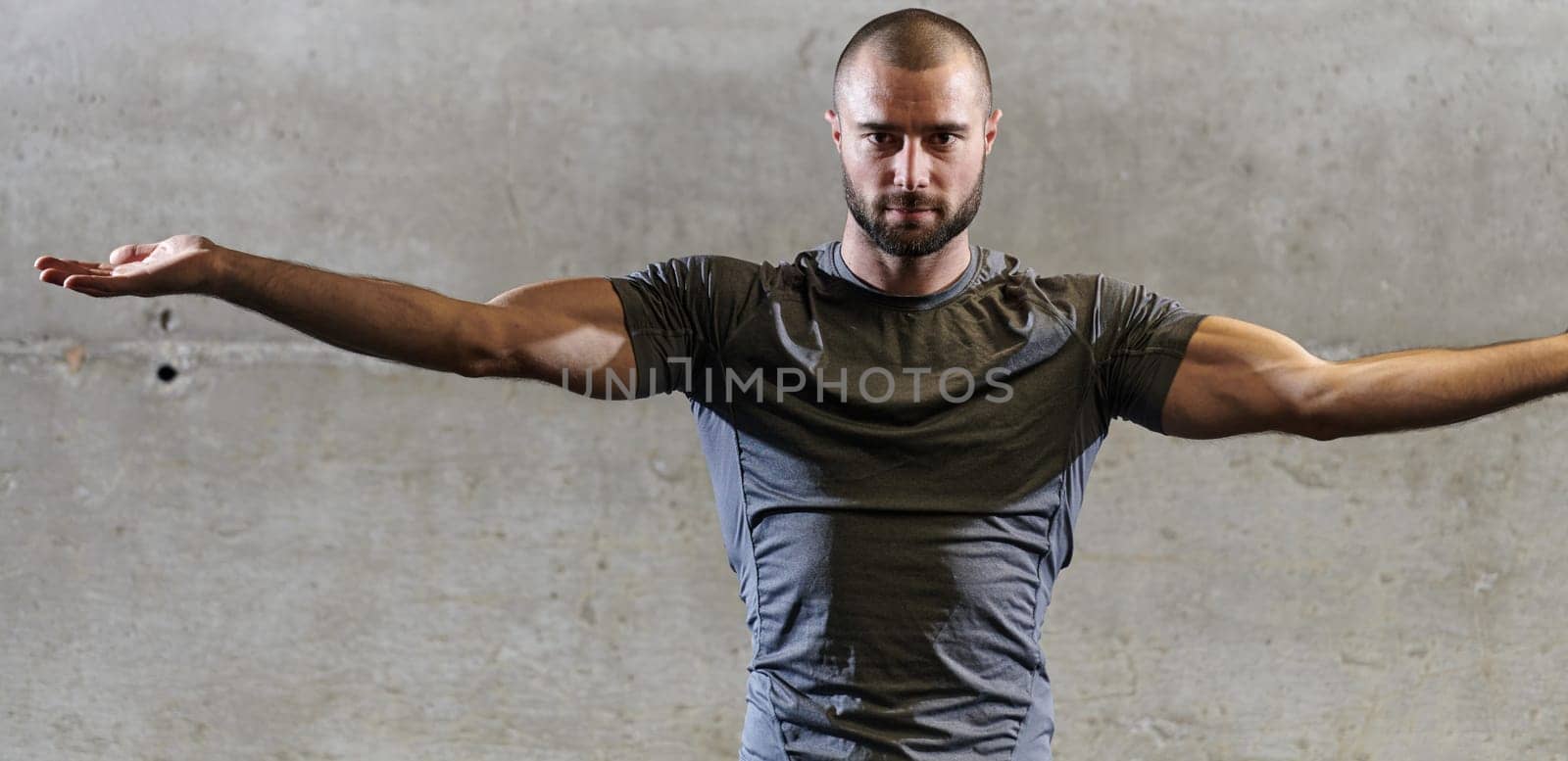 A muscular man working stretching exercises for his arms and body muscles in modern gym by dotshock