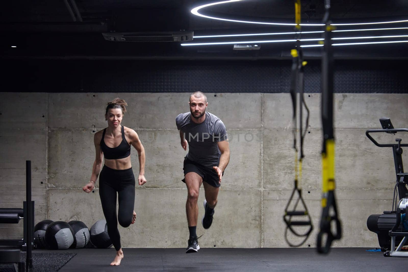 A fit couple in a modern gym, engaging in running exercises and showcasing their athletic prowess with a dynamic start. by dotshock