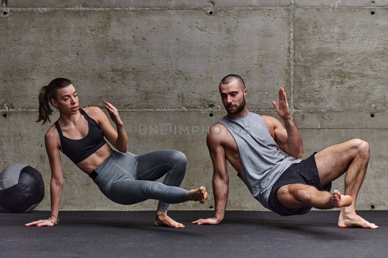 An attractive couple in the gym engaging in various stretching exercises together, showcasing their dedication to fitness, flexibility, and overall wellbeing. With synchronized movements, they demonstrate coordination, balance, and endurance while supporting and motivating each other on their fitness journey.