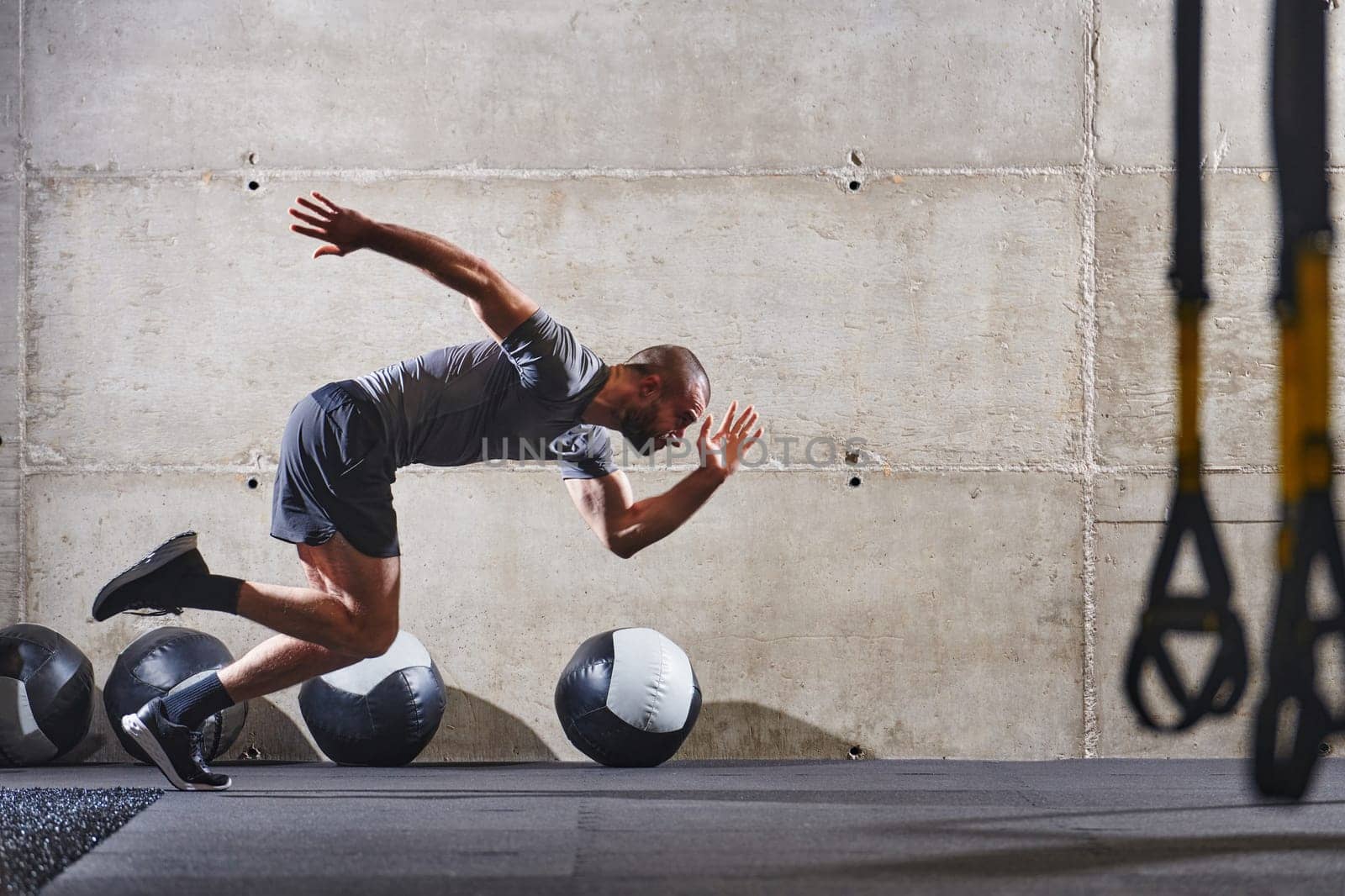 A muscular man captured in air as he jumps in a modern gym, showcasing his athleticism, power, and determination through a highintensity fitness routine.