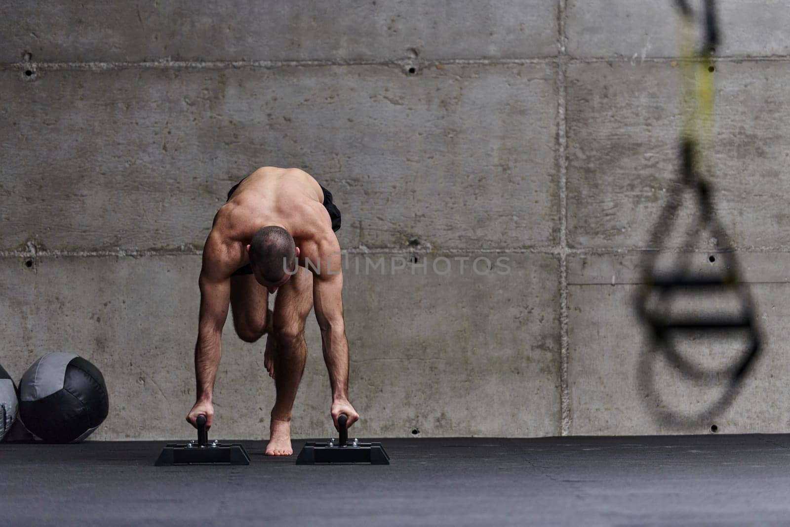 A muscular man in a handstand position, showcasing his exceptional balance and body control while performing a variety of exercises to enhance his overall body stability and strength in a modern gym.