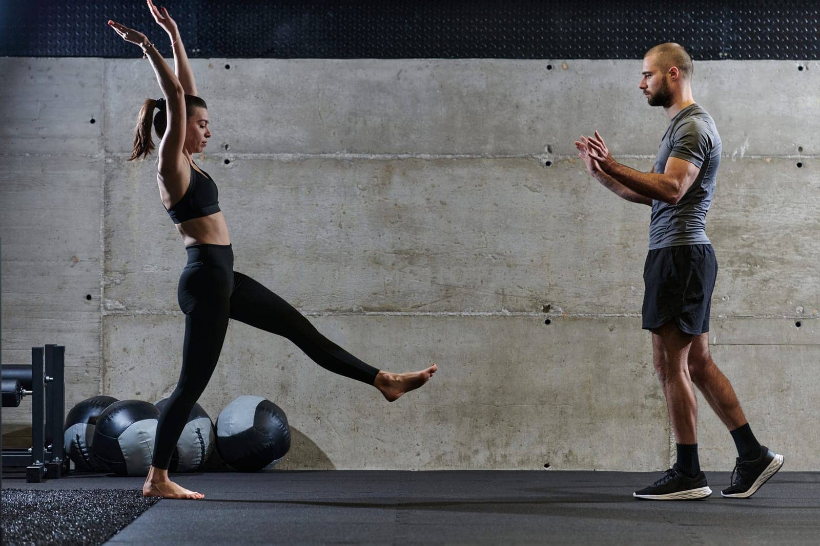 A muscular man assisting a fit woman in a modern gym as they engage in various body exercises and muscle stretches, showcasing their dedication to fitness and benefiting from teamwork and support by dotshock