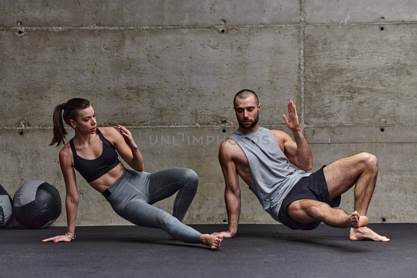 An attractive couple in the gym engaging in various stretching exercises together, showcasing their dedication to fitness, flexibility, and overall well-being. With synchronized movements, they demonstrate coordination, balance, and endurance while supporting and motivating each other on their fitness journey by dotshock