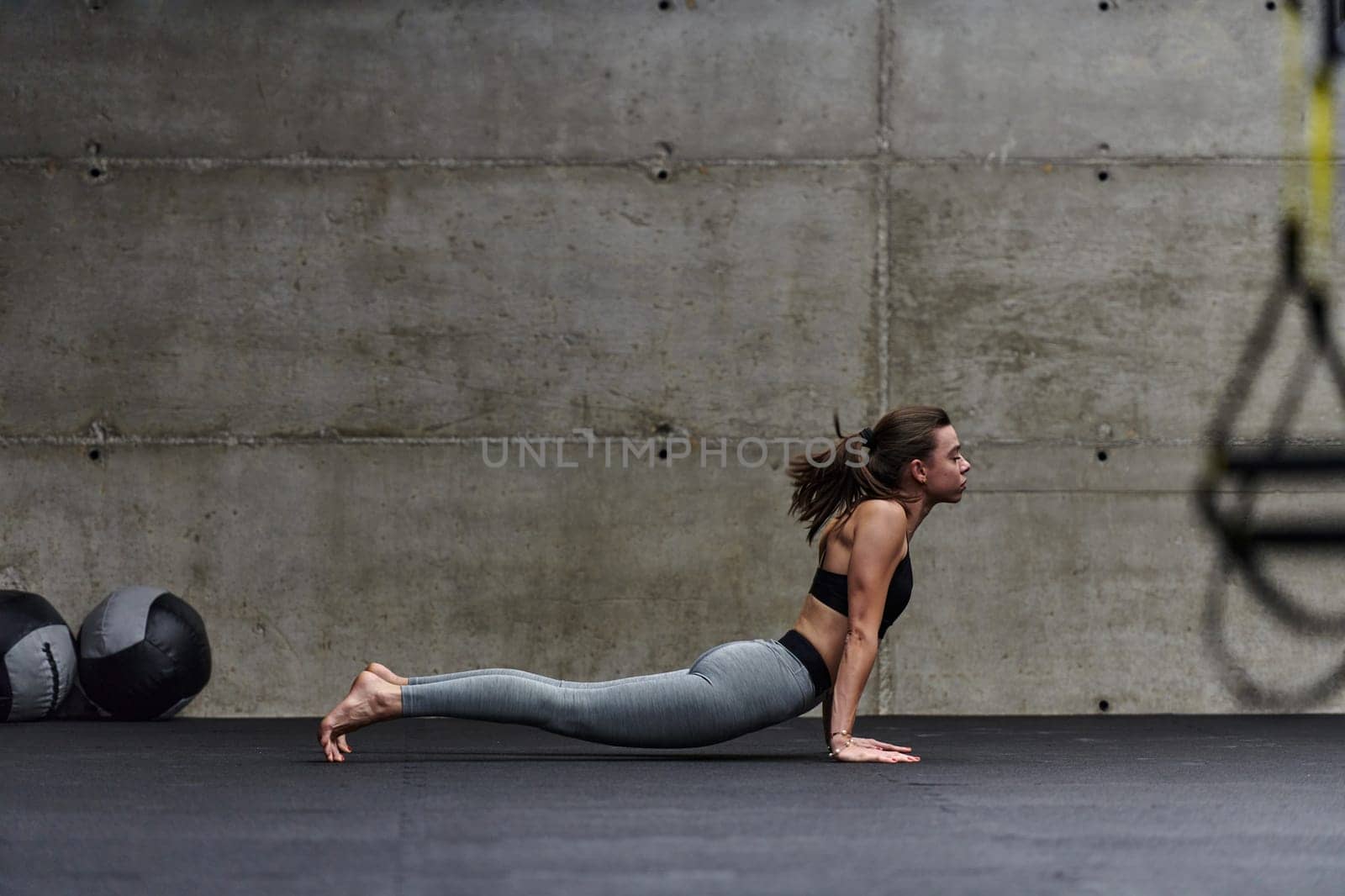 Fit woman in a modern gym working flexibility and strength through various exercises, demonstrating her commitment to fitness.