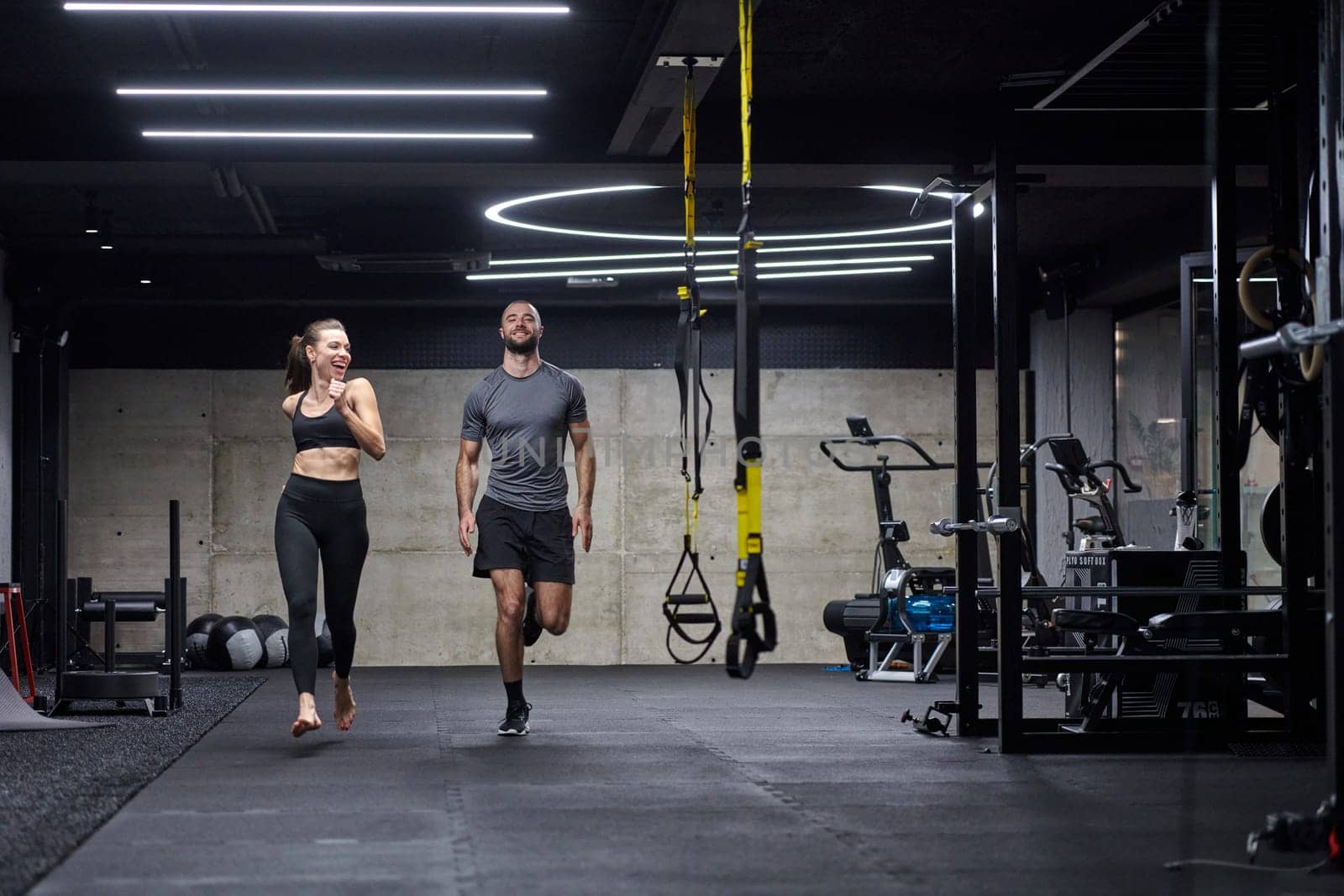 A fit couple in a modern gym, engaging in running exercises and showcasing their athletic prowess with a dynamic start. by dotshock