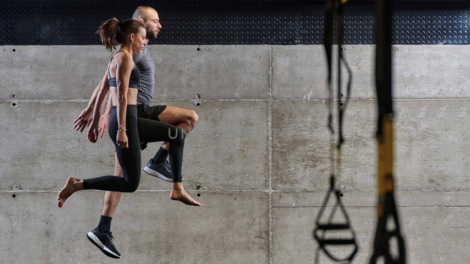 A fit couple exercising various types of jumps in a modern gym, demonstrating their physical fitness, strength, and athletic performance.