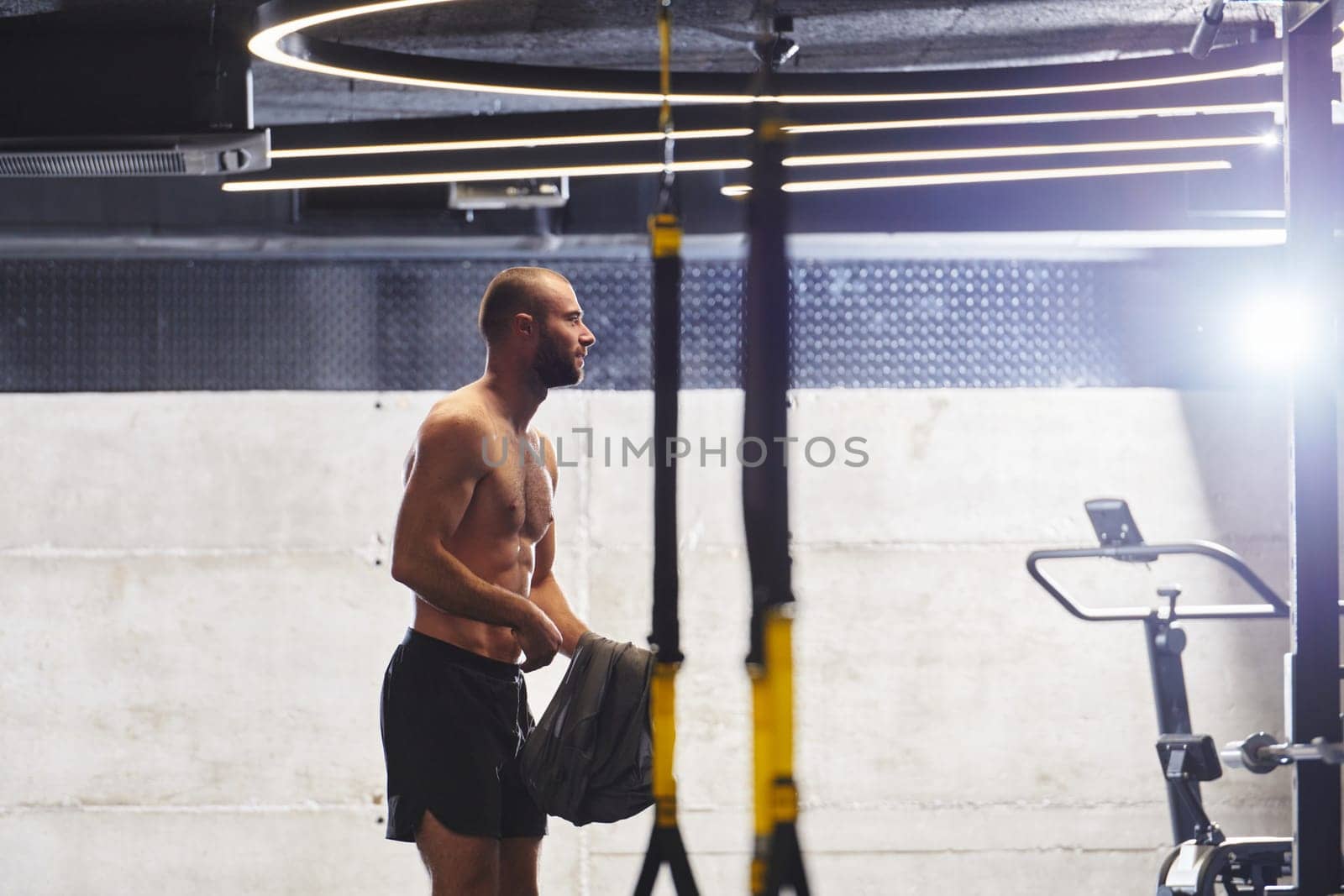 A muscular man in the gym, preparing for his workout, exudes determination and focus as he gets ready to push his limits and achieve his fitness goals