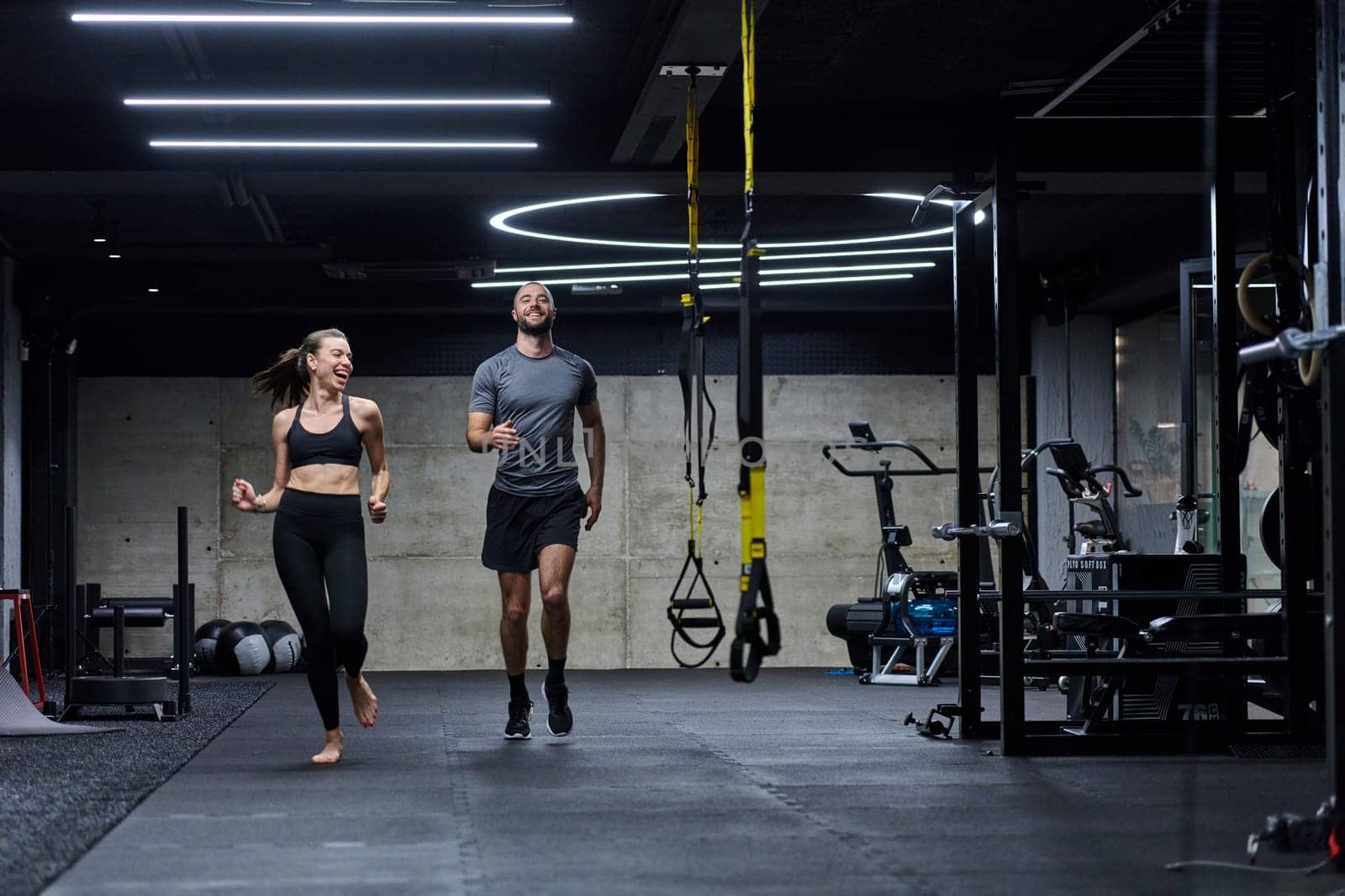 A fit couple in a modern gym, engaging in running exercises and showcasing their athletic prowess with a dynamic start. by dotshock