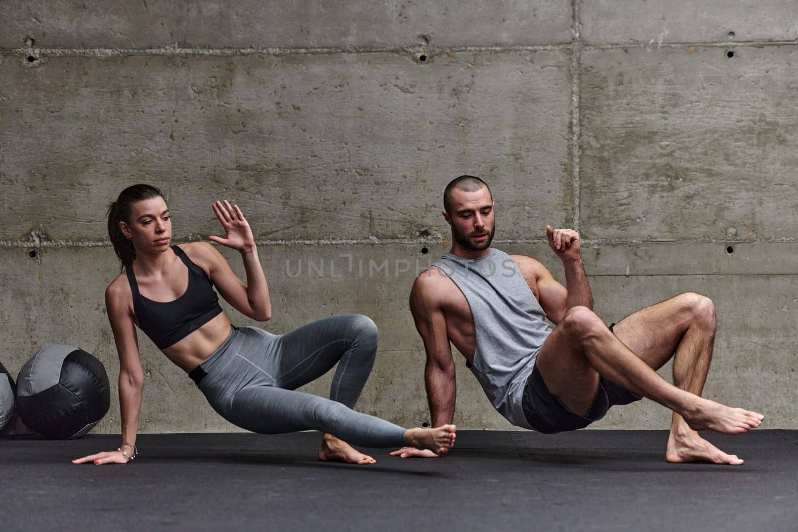 An attractive couple in the gym engaging in various stretching exercises together, showcasing their dedication to fitness, flexibility, and overall wellbeing. With synchronized movements, they demonstrate coordination, balance, and endurance while supporting and motivating each other on their fitness journey.