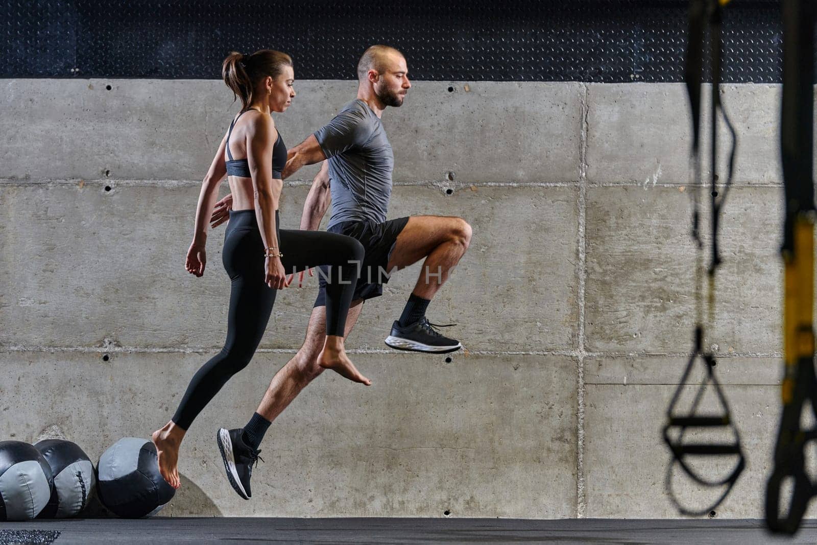 A fit couple exercising various types of jumps in a modern gym, demonstrating their physical fitness, strength, and athletic performance.