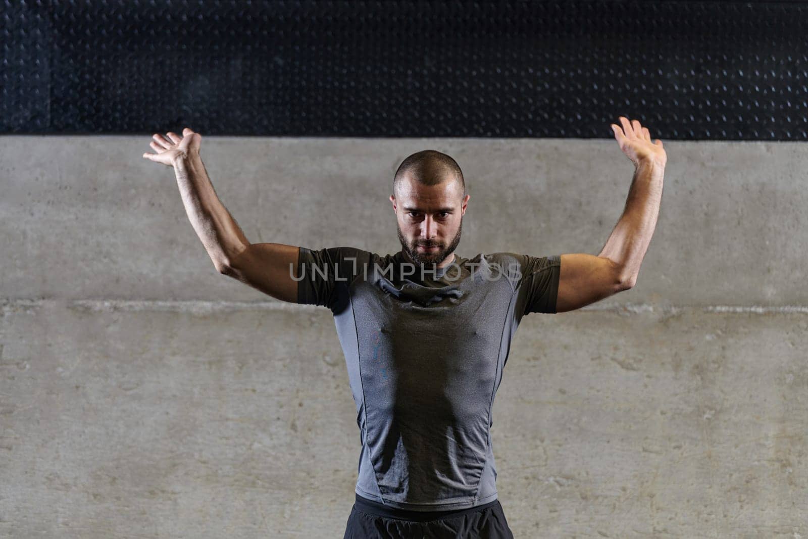 A muscular man working stretching exercises for his arms and body muscles in modern gym .