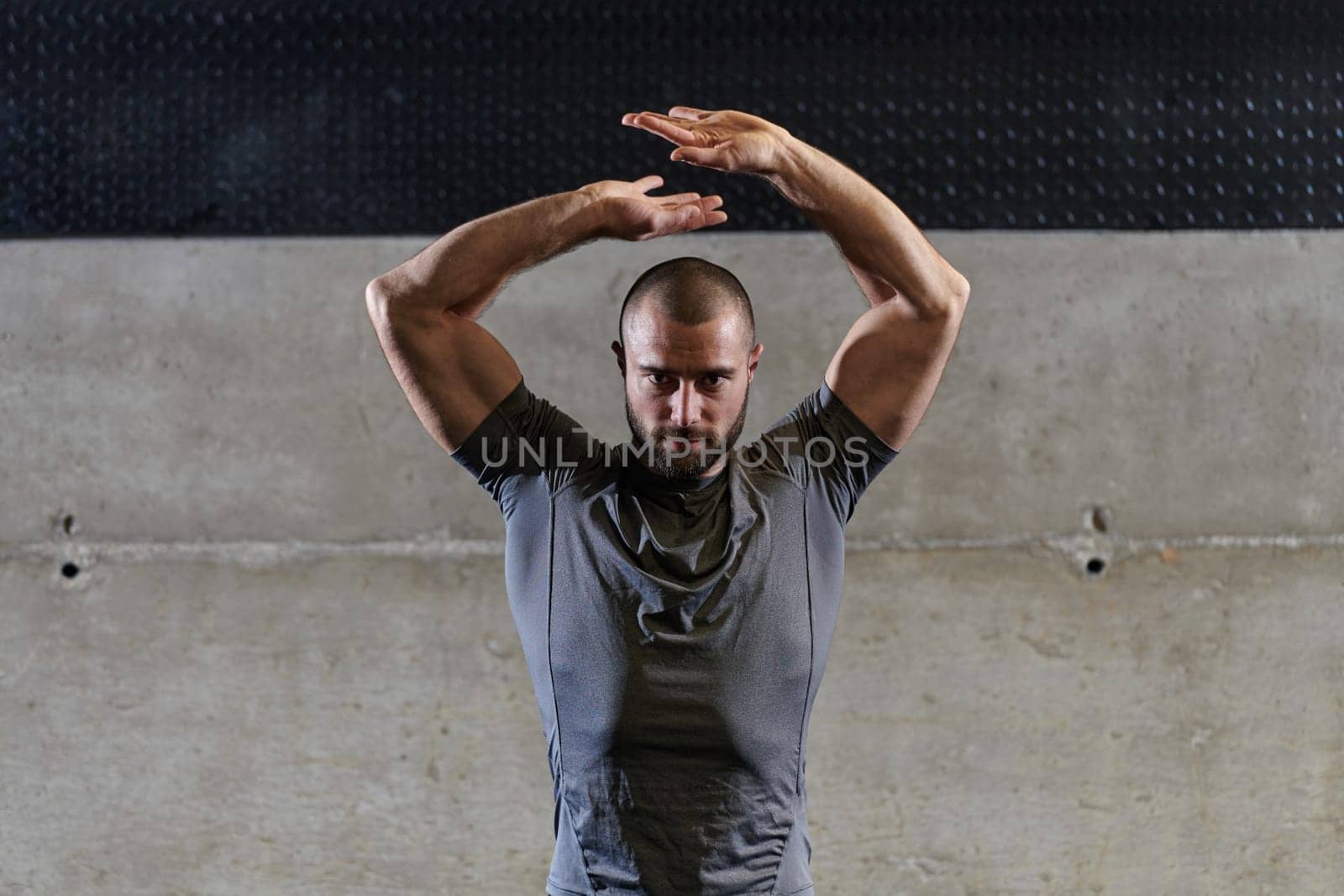 A muscular man working stretching exercises for his arms and body muscles in modern gym .