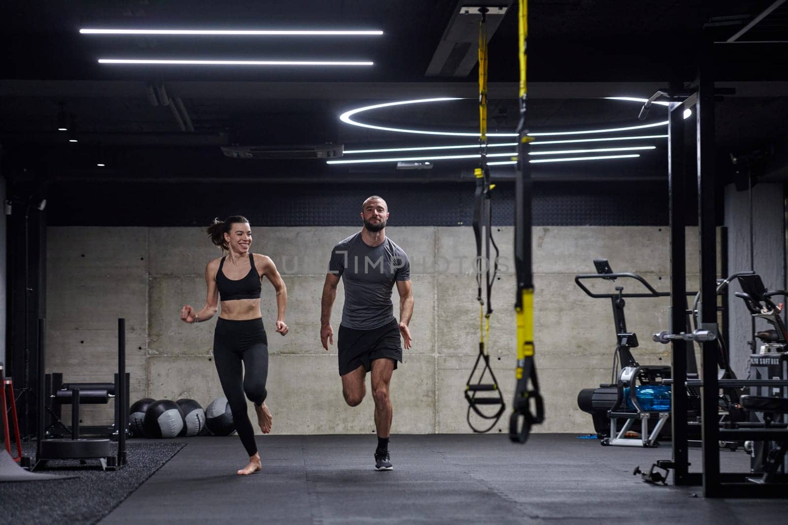 A fit couple in a modern gym, engaging in running exercises and showcasing their athletic prowess with a dynamic start. by dotshock