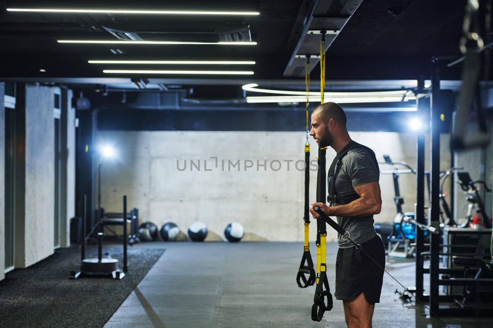 A muscular man in the gym, preparing for his workout, exudes determination and focus as he gets ready to push his limits and achieve his fitness goals