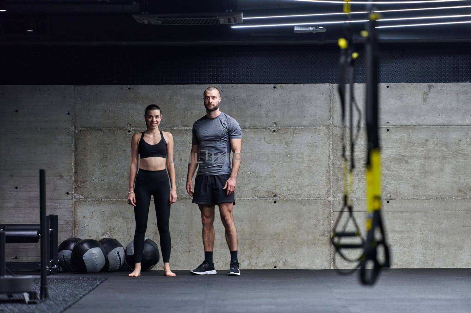 Muscular man and fit woman in a conversation before commencing their training session in a modern gym. by dotshock