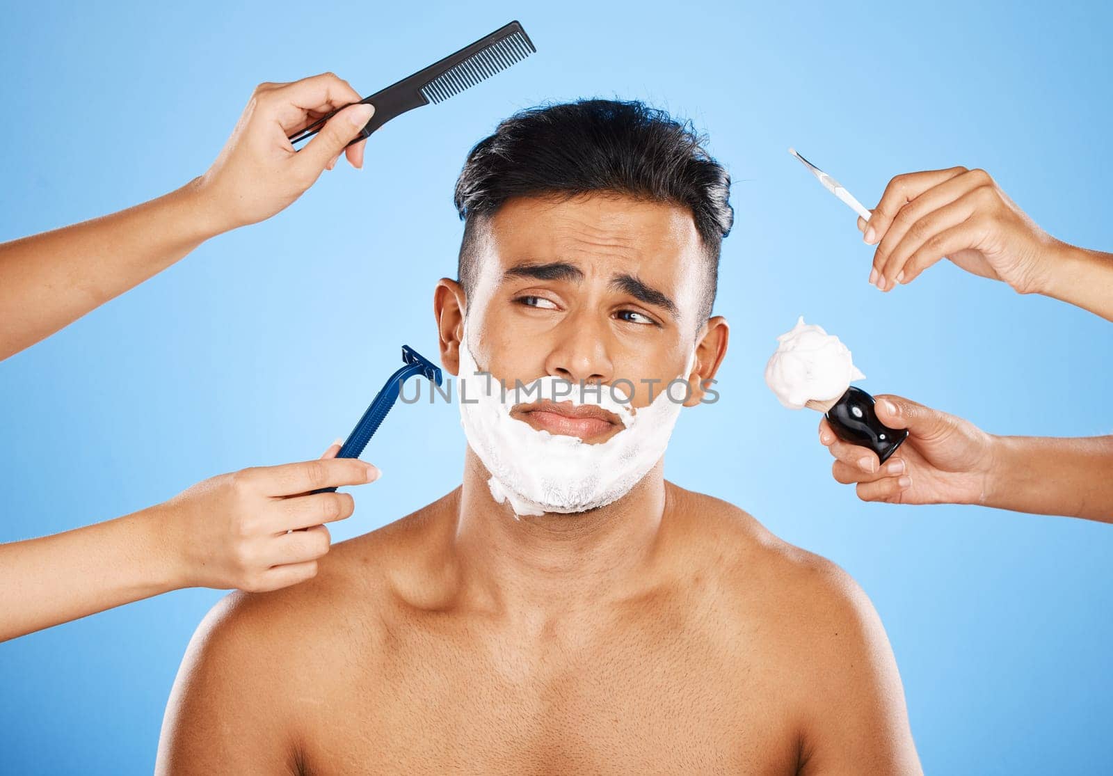 Face, shave and grooming with hands holding equipment for shaving or brushing hair in studio on a blue background. Skincare, wellness and luxury with an unhappy male customer at the barber for beauty.