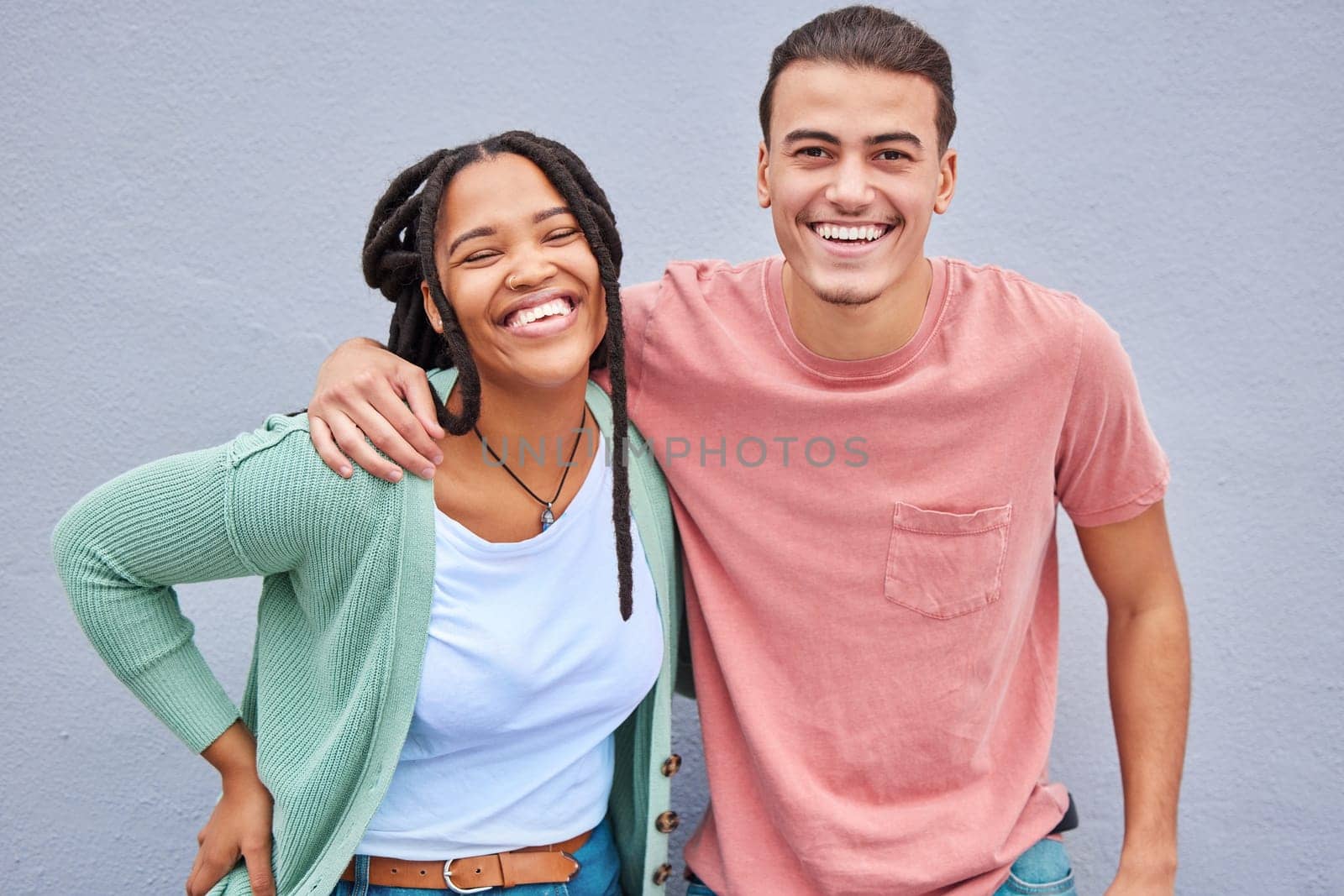 Love, romance and portrait of a happy couple by a wall in the city while on a vacation or weekend trip. Happiness, smile and interracial man and woman embracing while walking in town on a holiday