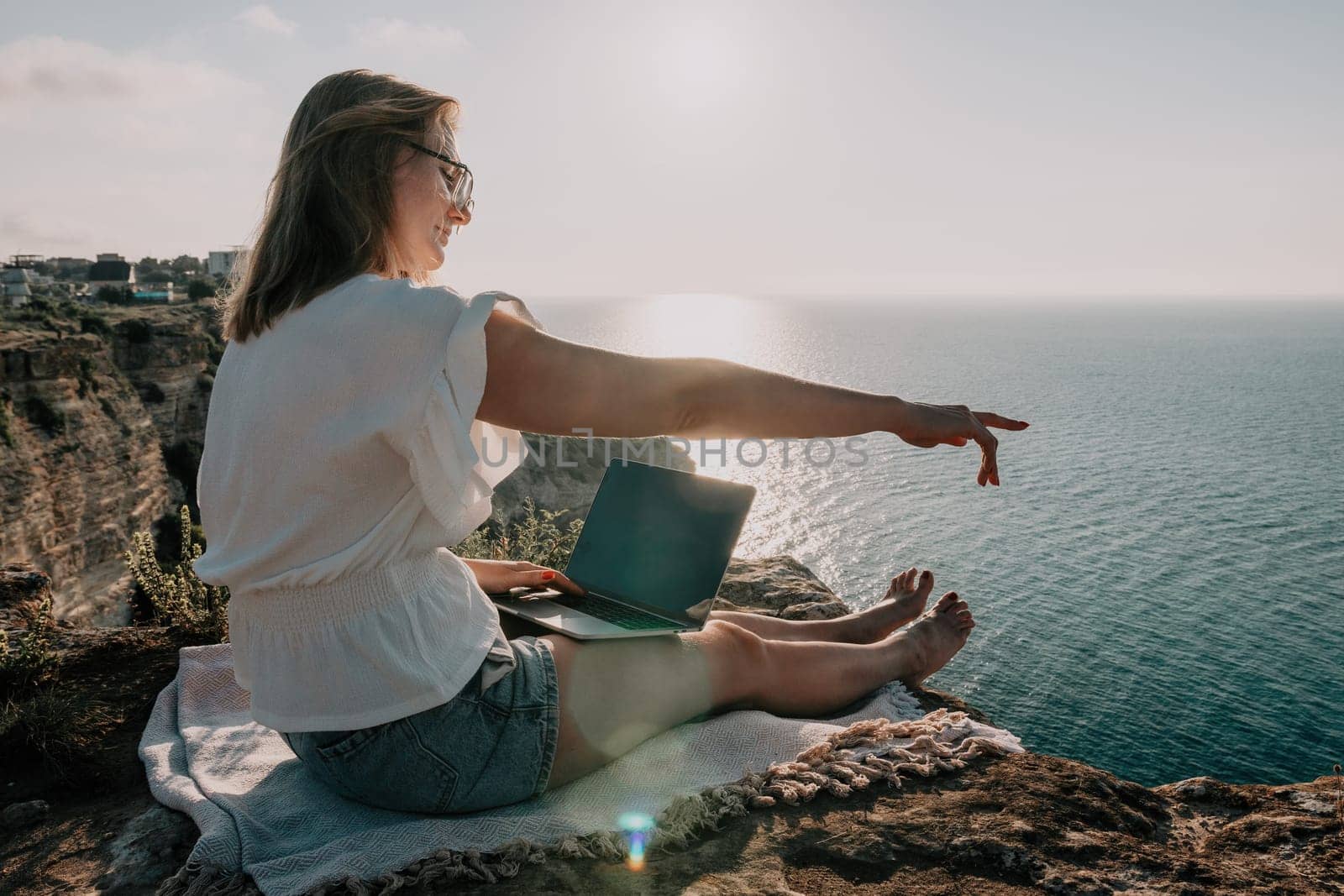 Woman sea laptop. Business woman working on laptop by sea at sunset. Close up on hands of pretty lady typing on computer outdoors summer day. Freelance, digital nomad, travel and holidays concept. by panophotograph