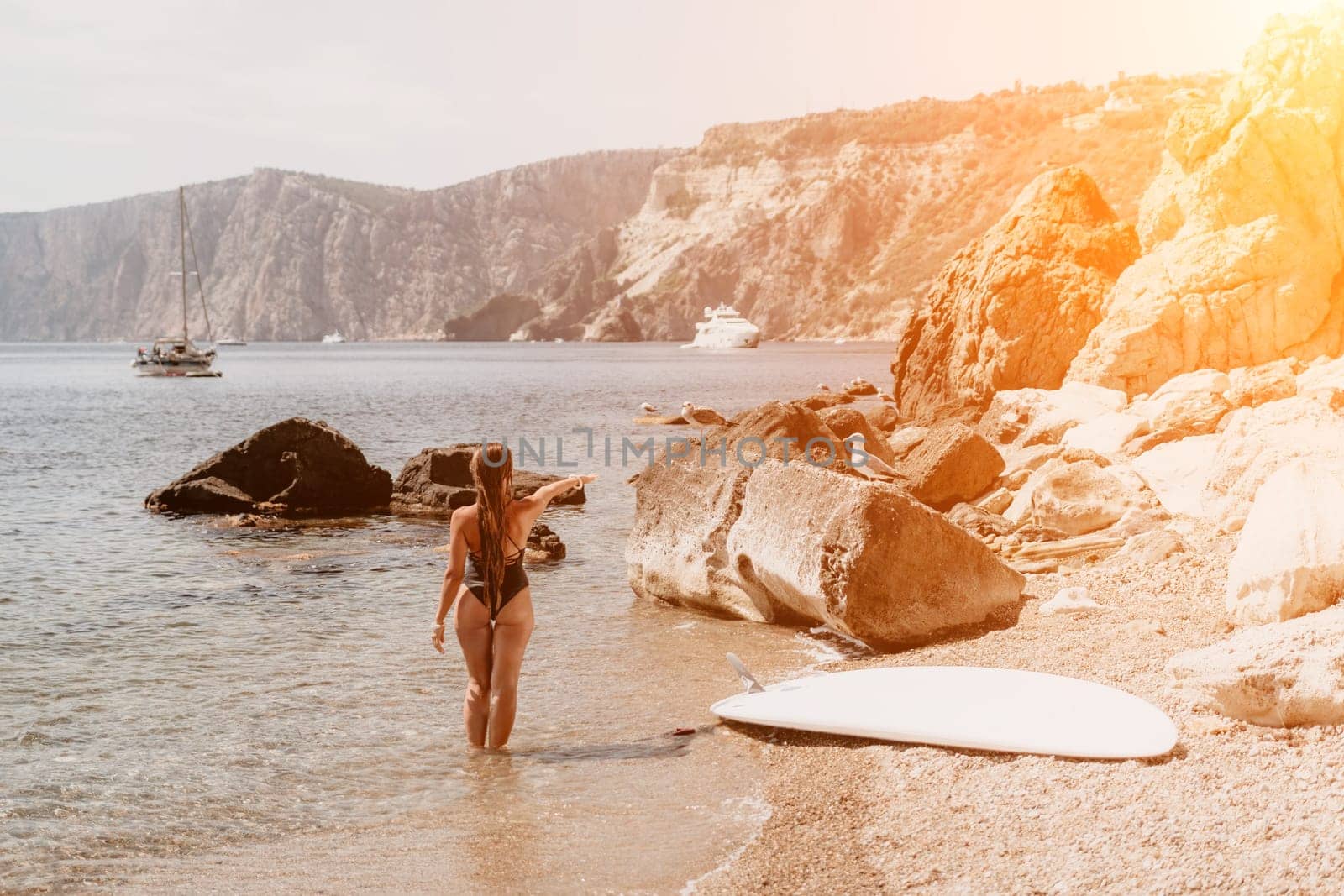 Woman travel sea. Young Happy woman in a long red dress posing on a beach near the sea on background of volcanic rocks, like in Iceland, sharing travel adventure journey