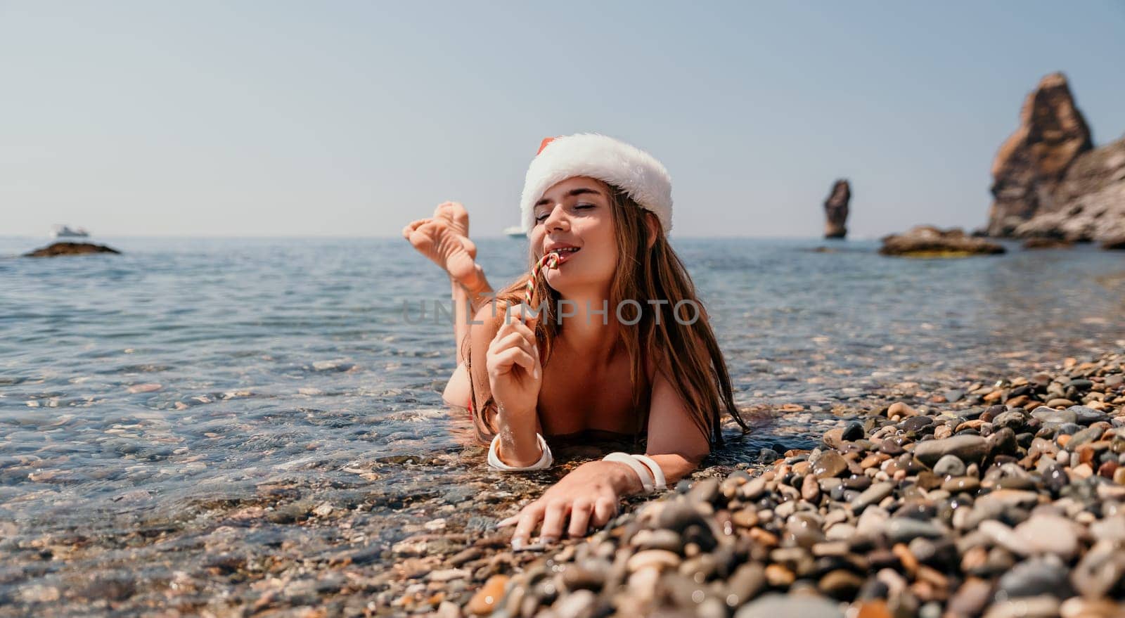 Woman travel sea. Happy tourist enjoy taking picture on the beach for memories. Woman traveler in Santa hat looks at camera on the sea bay, sharing travel adventure journey by panophotograph