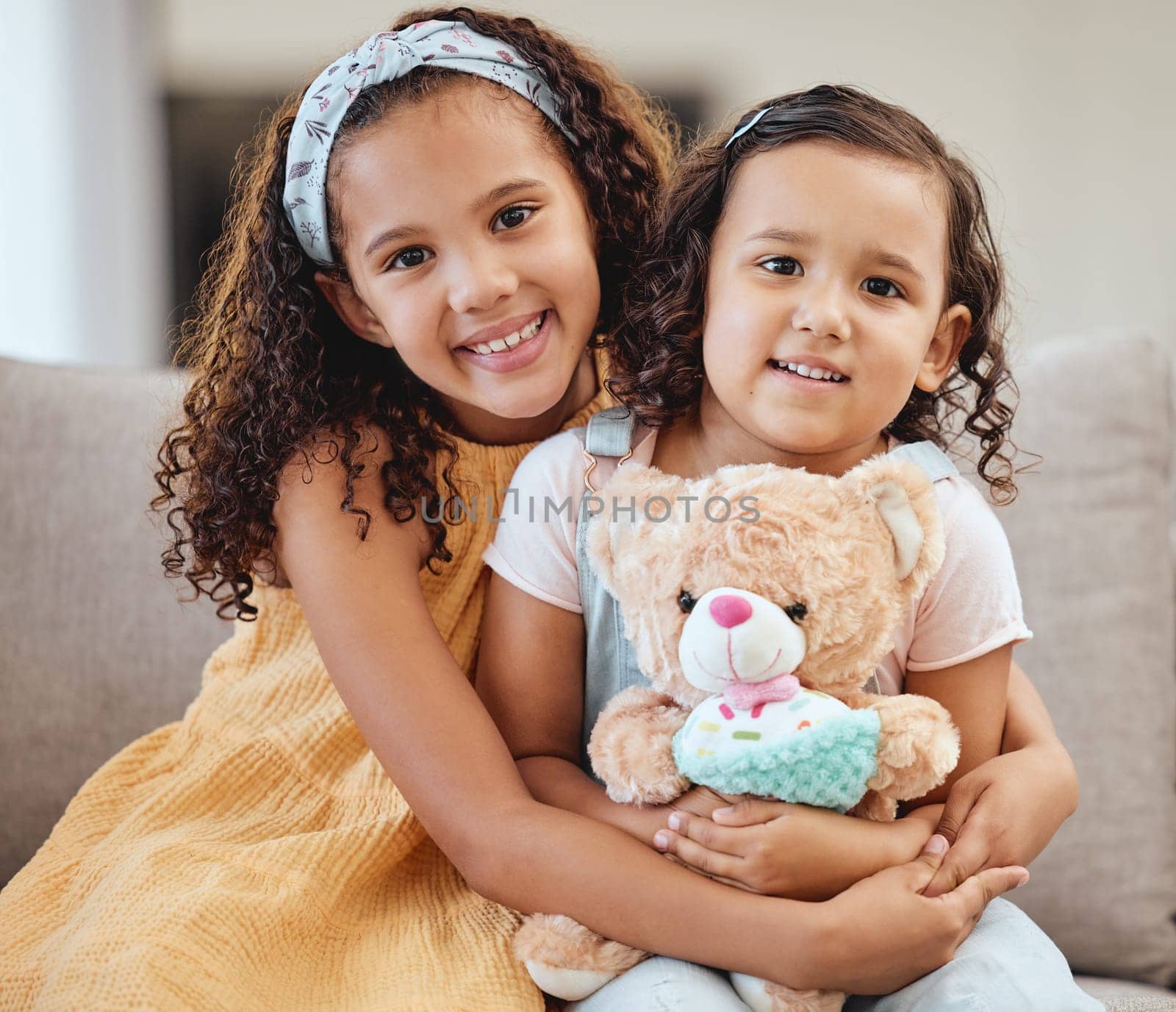 Family, children hug and portrait of girls on sofa in living room while holding teddy bear. Love, care and happy kids, sisters and siblings bonding, embrace and hugging on couch in lounge of house