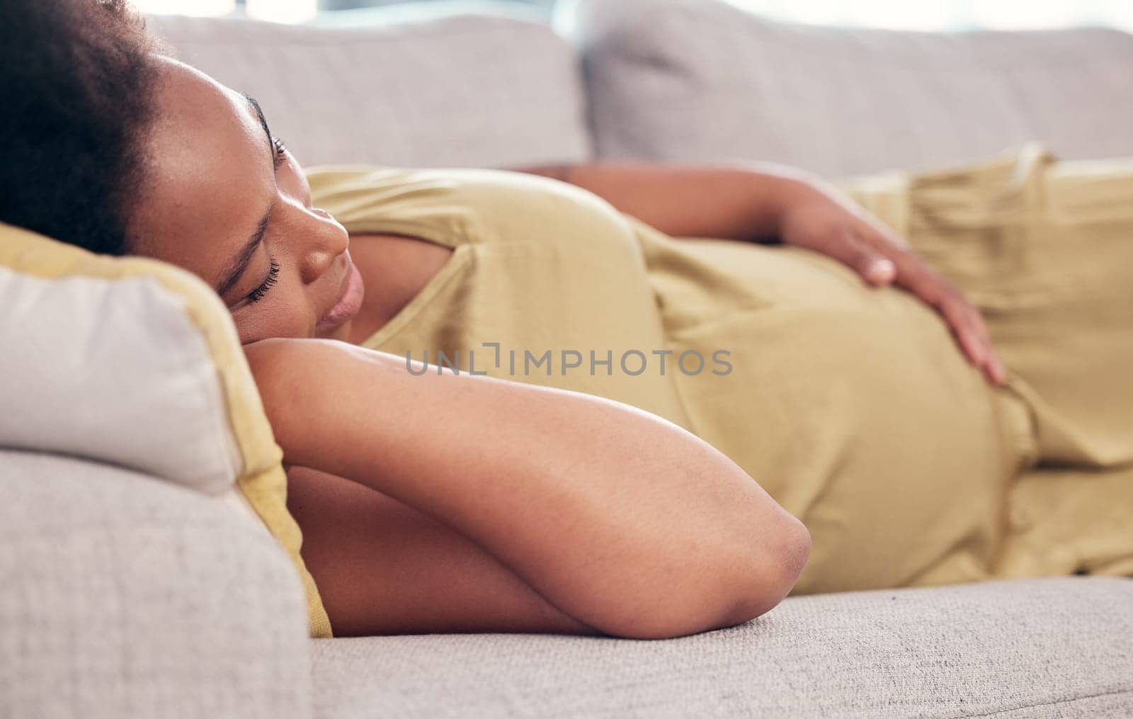 Pregnant, maternity and sleeping woman resting holding her tummy or stomach and relax expecting a baby. Home, pregnancy and lying on a couch or sofa in a house or apartment on a break in a lounge.