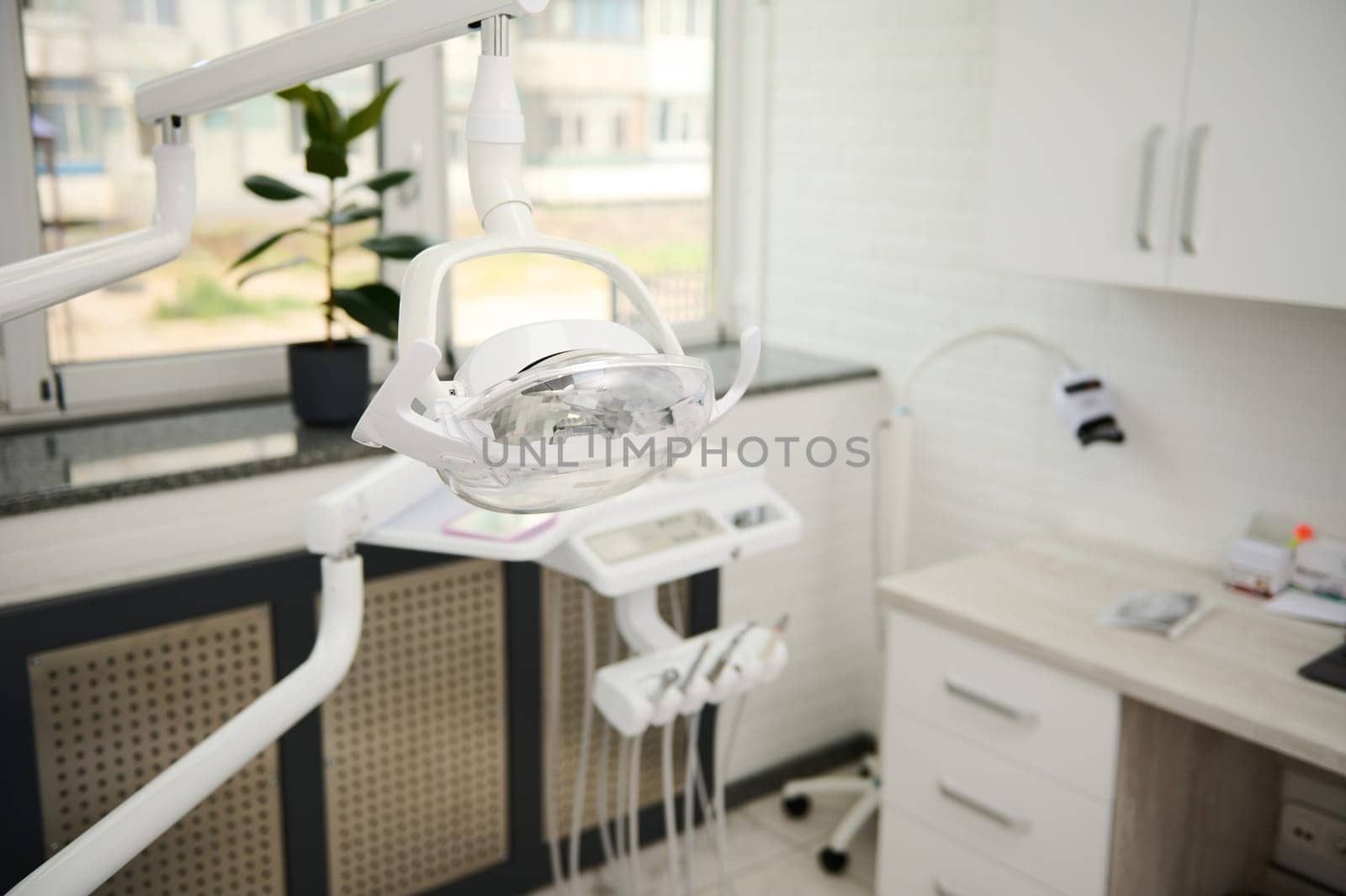 Focus on dental operating lamp with directional LED light. Interior of new modern dental clinic. Medical equipment by artgf
