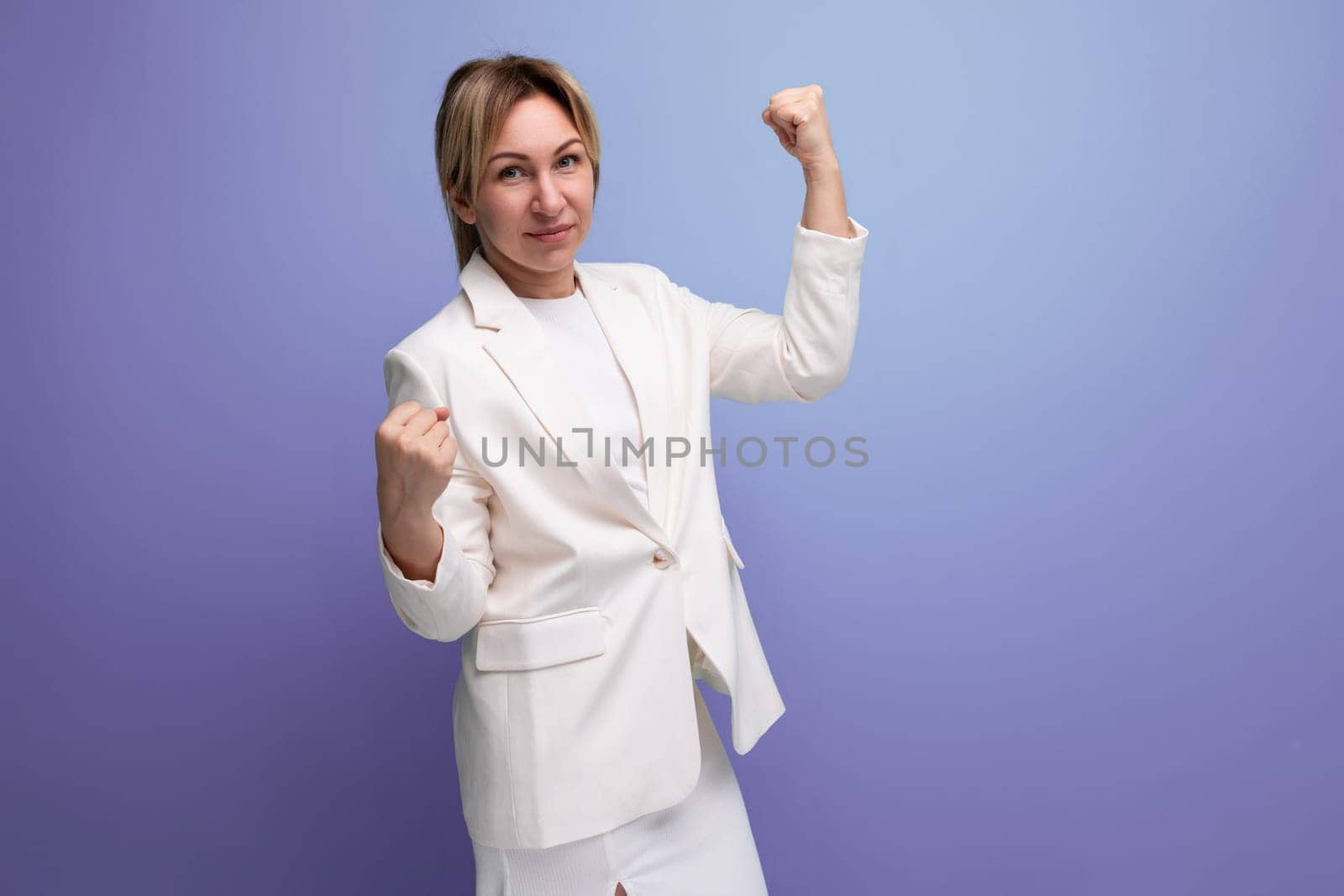 blond young business lady in an elegant jacket posing confidently on a studio background by TRMK