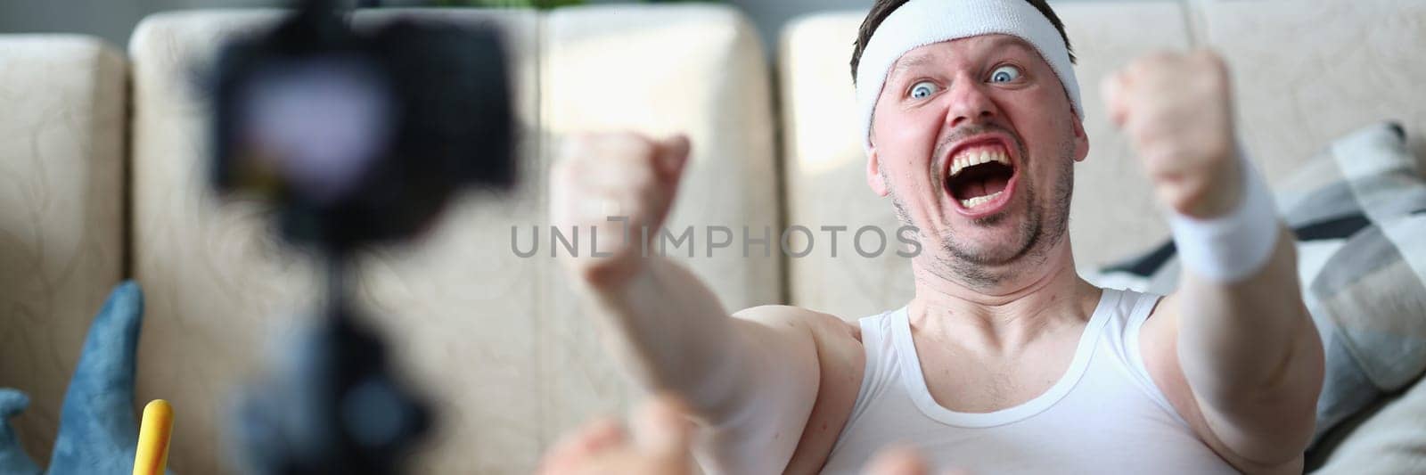 Motivated stubborn emotional man doing sports exercises in front of camera by kuprevich