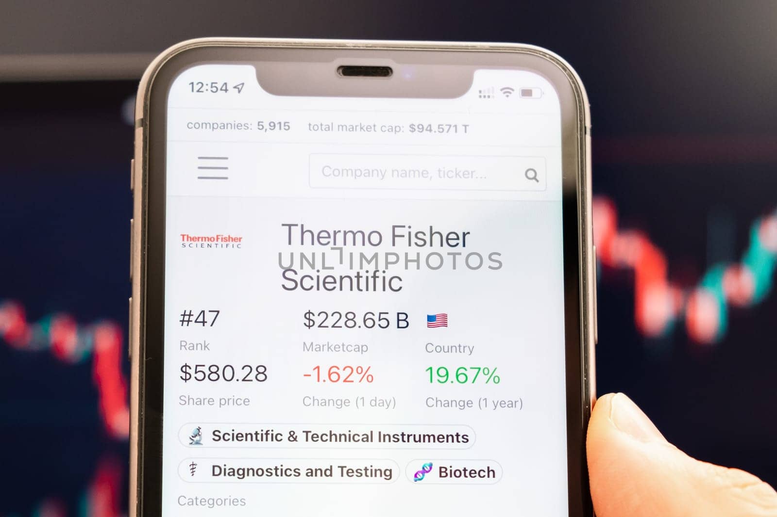 Thermo Fisher Scientific stock price on the screen of mobile phone in mans hand with changing stock market graphs on the background, February 2022, San Francisco, USA.