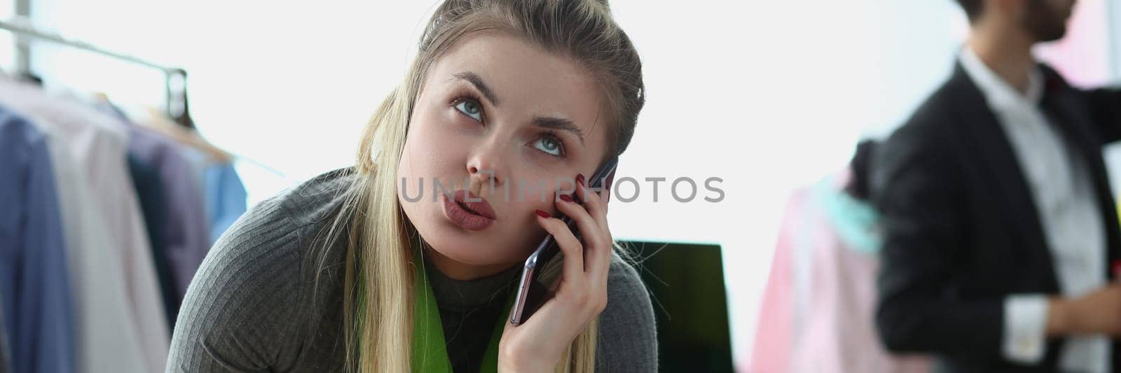 Creative designer manager stylist offers tailoring design option over phone. Seamstress woman talking to client on smartphone