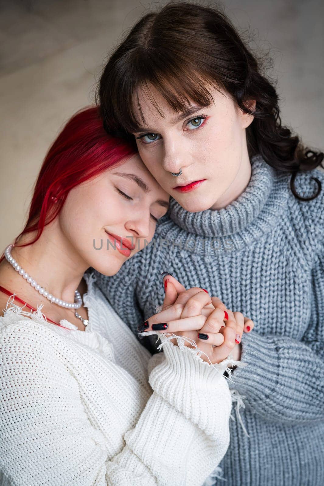 Portrait of two tenderly hugging women dressed in sweaters. Lesbian intimacy